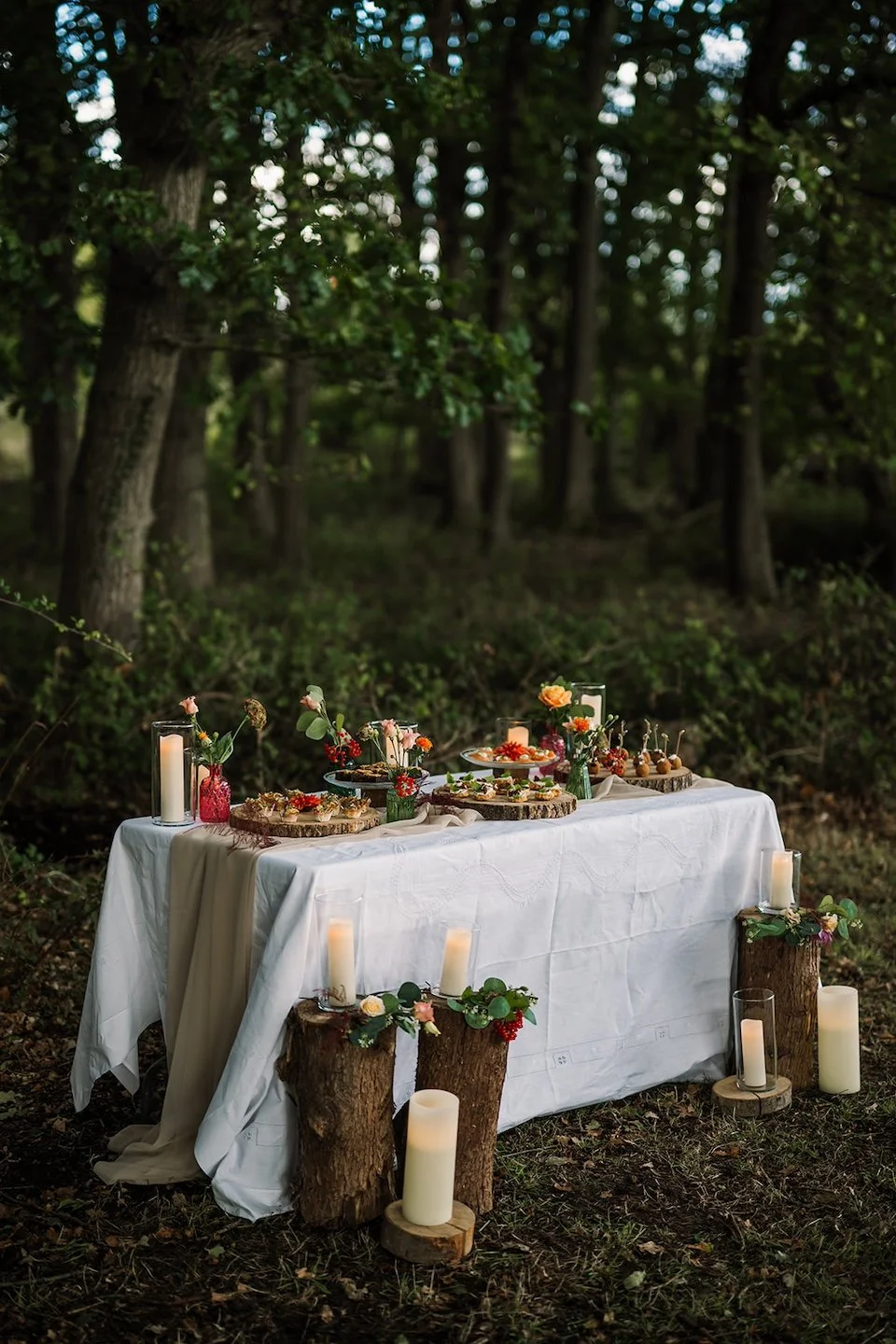 A woodland wedding table styled with candles, natural textures and seasonal details, creating a warm, eco-friendly celebration planned by Wild Soul Weddings, eco wedding planners in the UK. Rach Elizabeth Photography.