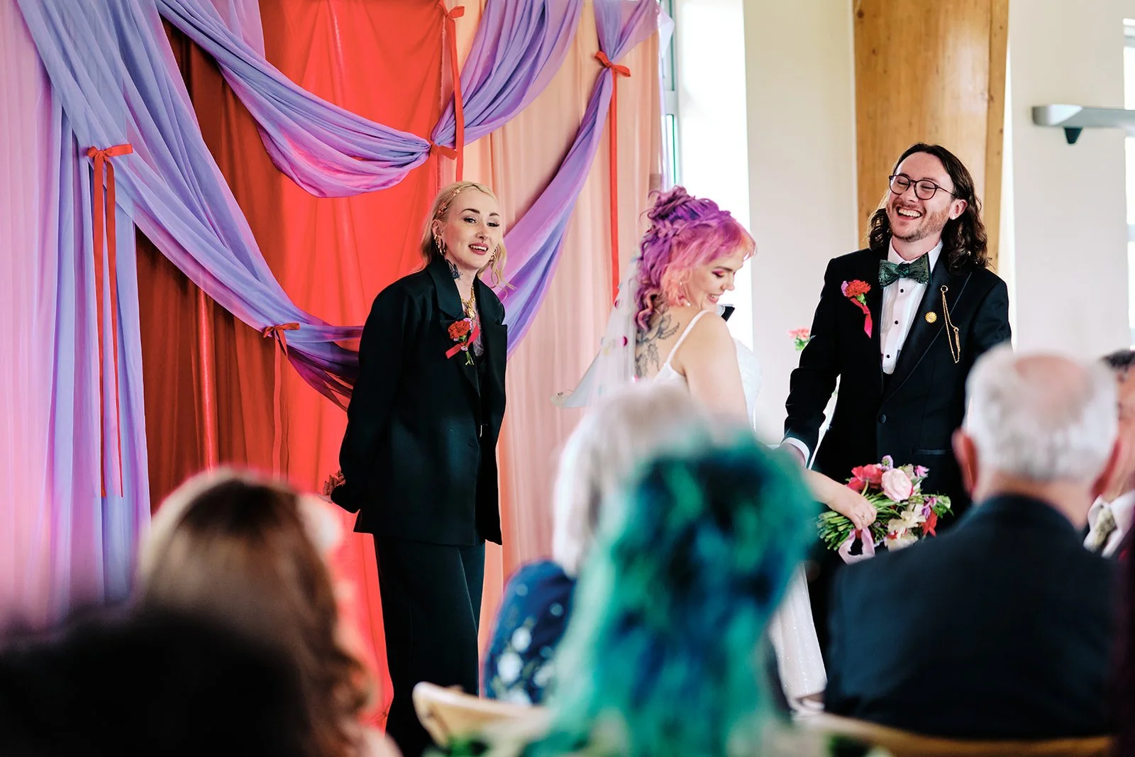 Orange Tree Weddings styling and décor showcasing a vibrant modern wedding ceremony, with layered lilac and coral draping, bold florals and contemporary styling for a joyful, personality-led celebration.