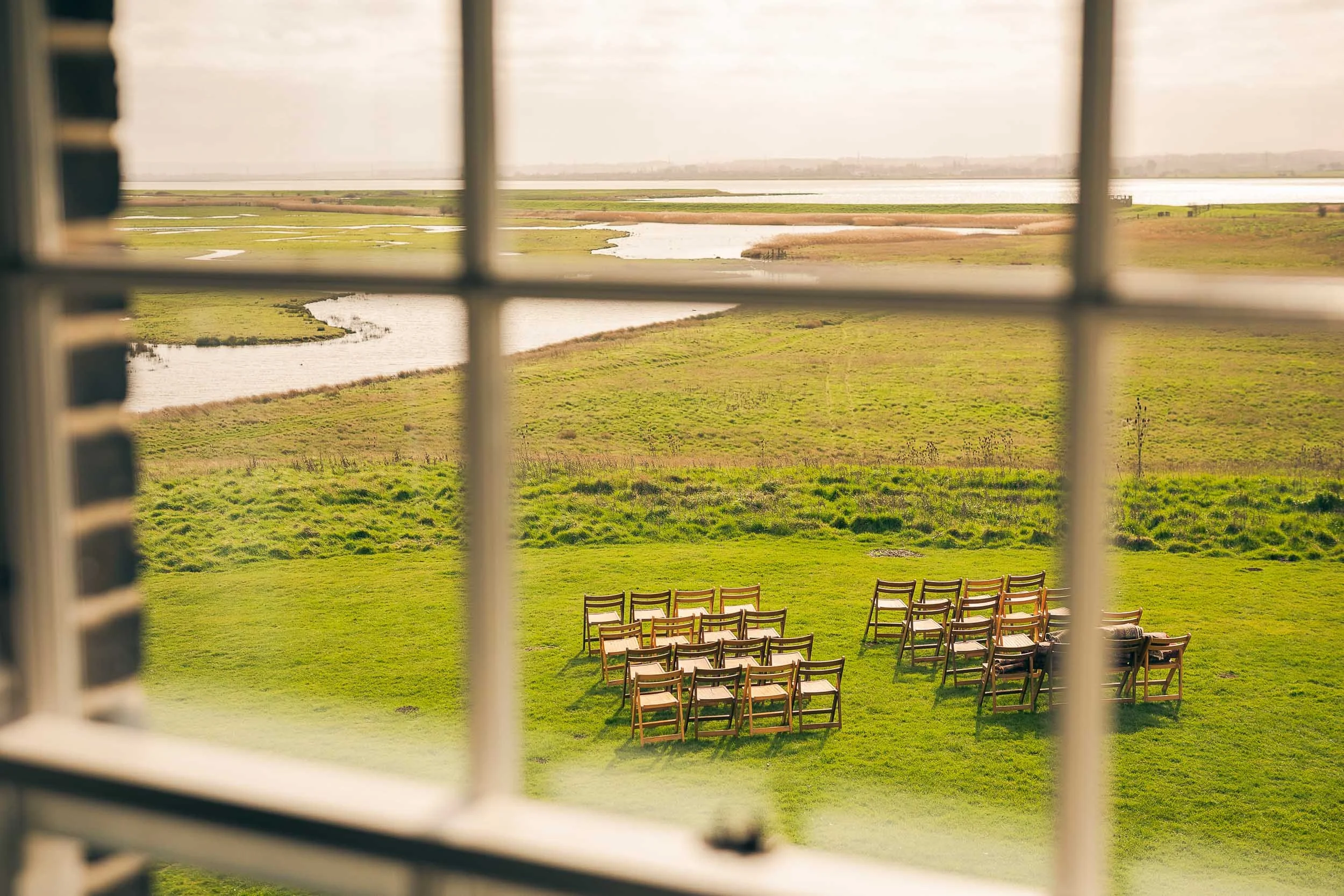 Wooden chairs set out on the lawn for an outdoor wedding ceremony at Elmley Nature Reserve in Kent