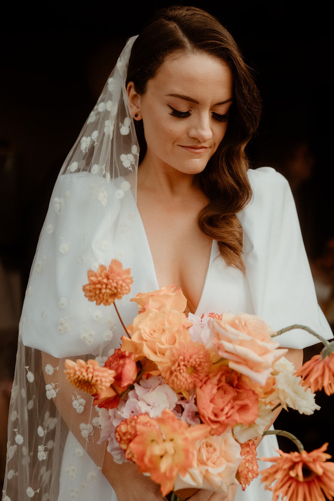 A soft and romantic bridal portrait featuring makeup by Powder Blue Artistry, with flawless glowing skin, defined lashes, and natural tones. The elegant look complements the bride’s floral veil and warm bouquet, creating timeless beauty perfect for m