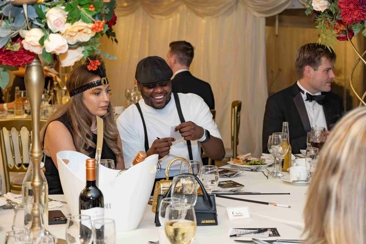Moonstone Murders wedding guests dressed in vintage-inspired attire solving clues at their table during an immersive murder mystery experience.