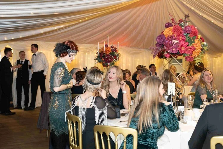 Moonstone Murders performer in 1920s flapper-style costume engaging with wedding guests during an immersive murder mystery experience.