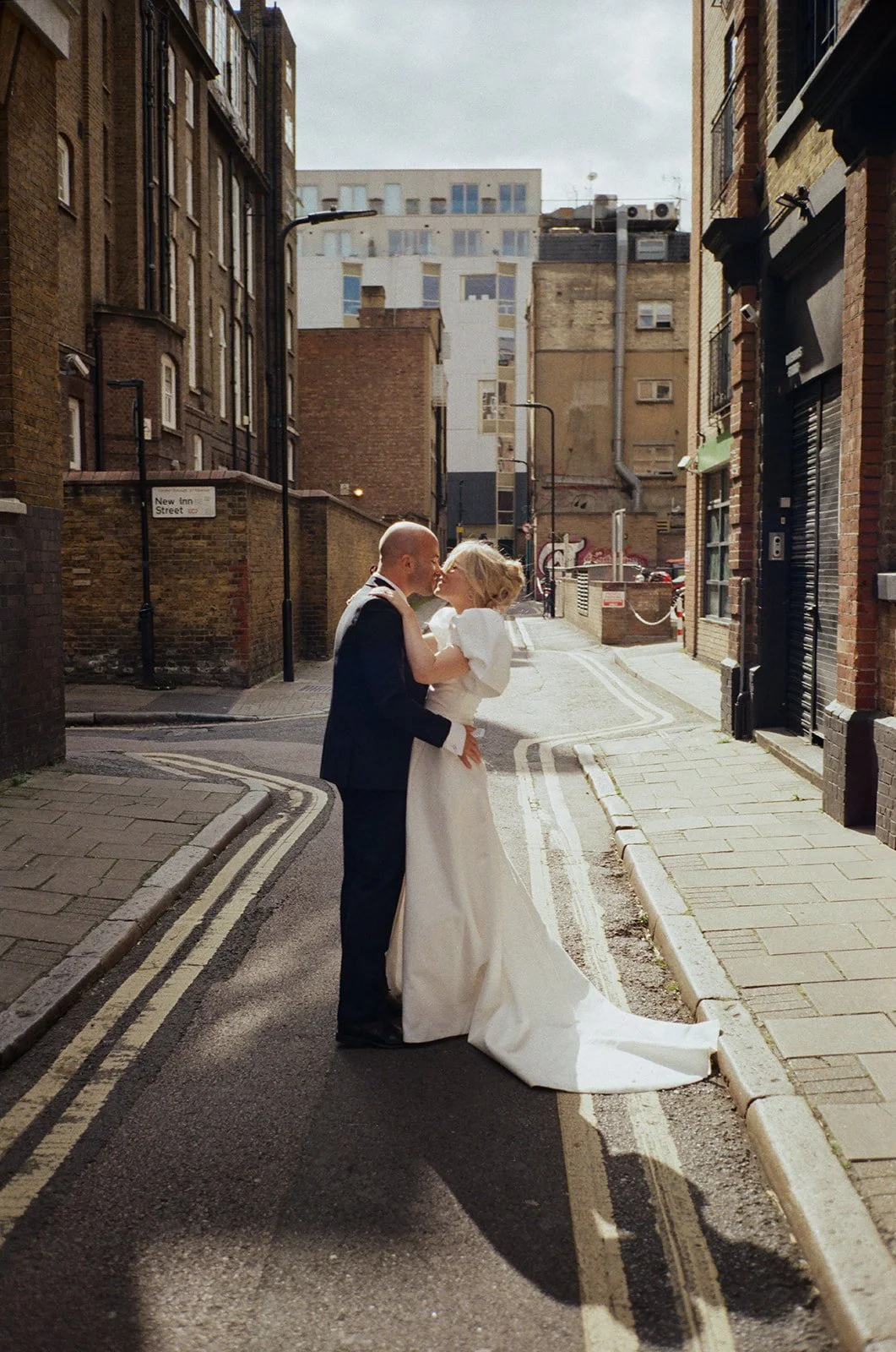 A couple is shown celebrating in a series of lively wedding scenes that move between cinematic city streets and soft interior spaces as golden light, bold color and gentle motion shape the atmosphere while the bride’s flowing gown and bouquet texture