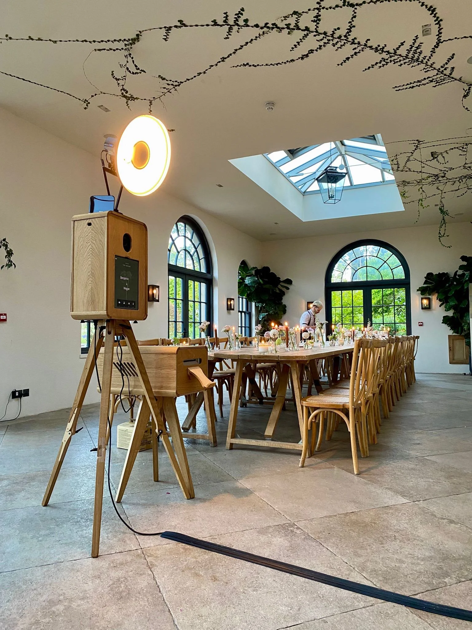 The Viva La Booth setup complements a stunning wedding venue filled with natural light and elegant rustic decor. The handcrafted wooden photobooth adds a warm, vintage touch to the modern space, ready to capture timeless memories for guests throughou