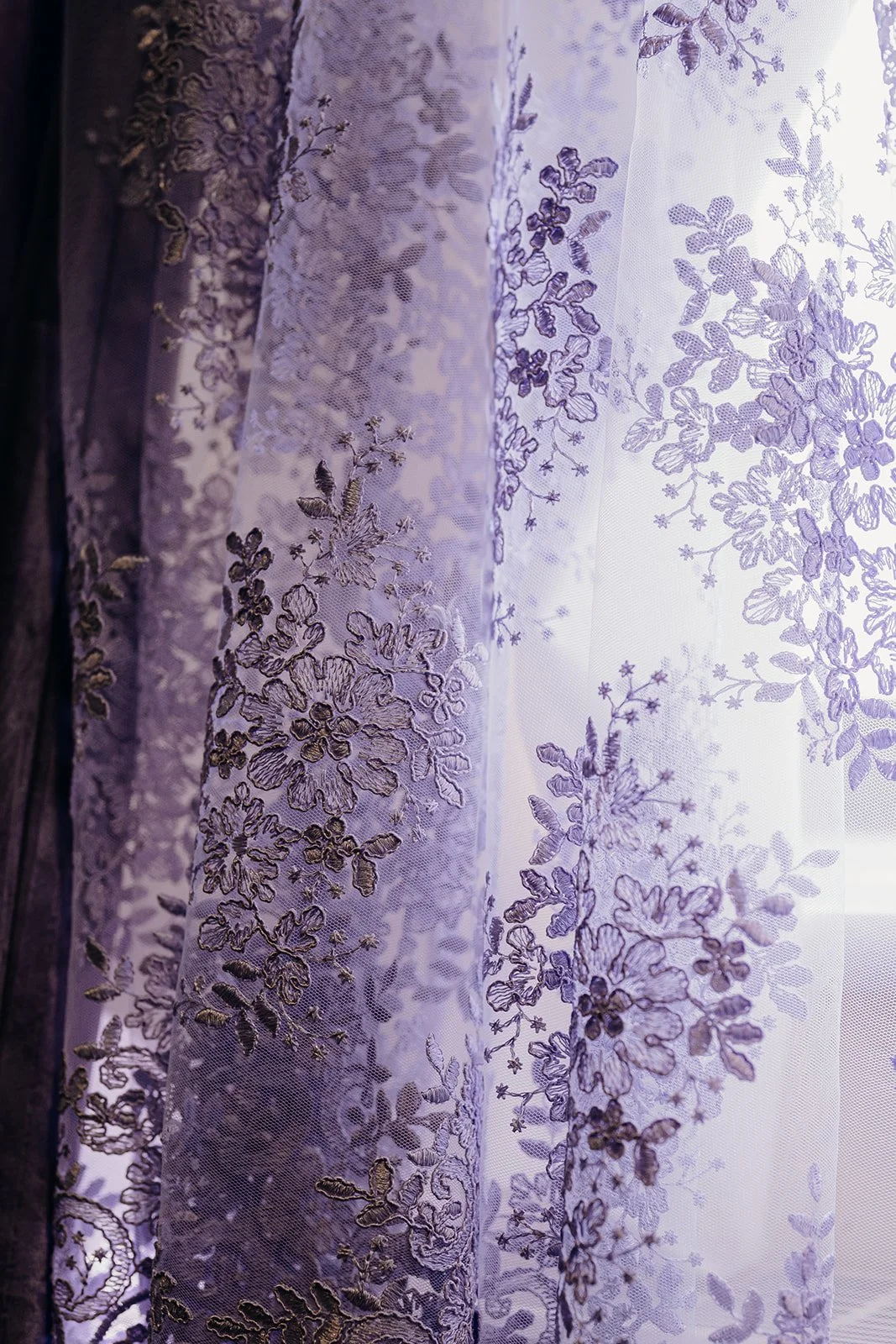 A close up image of a lilac lace overskirt that was added to a bride's ivory wedding jumpsuit.