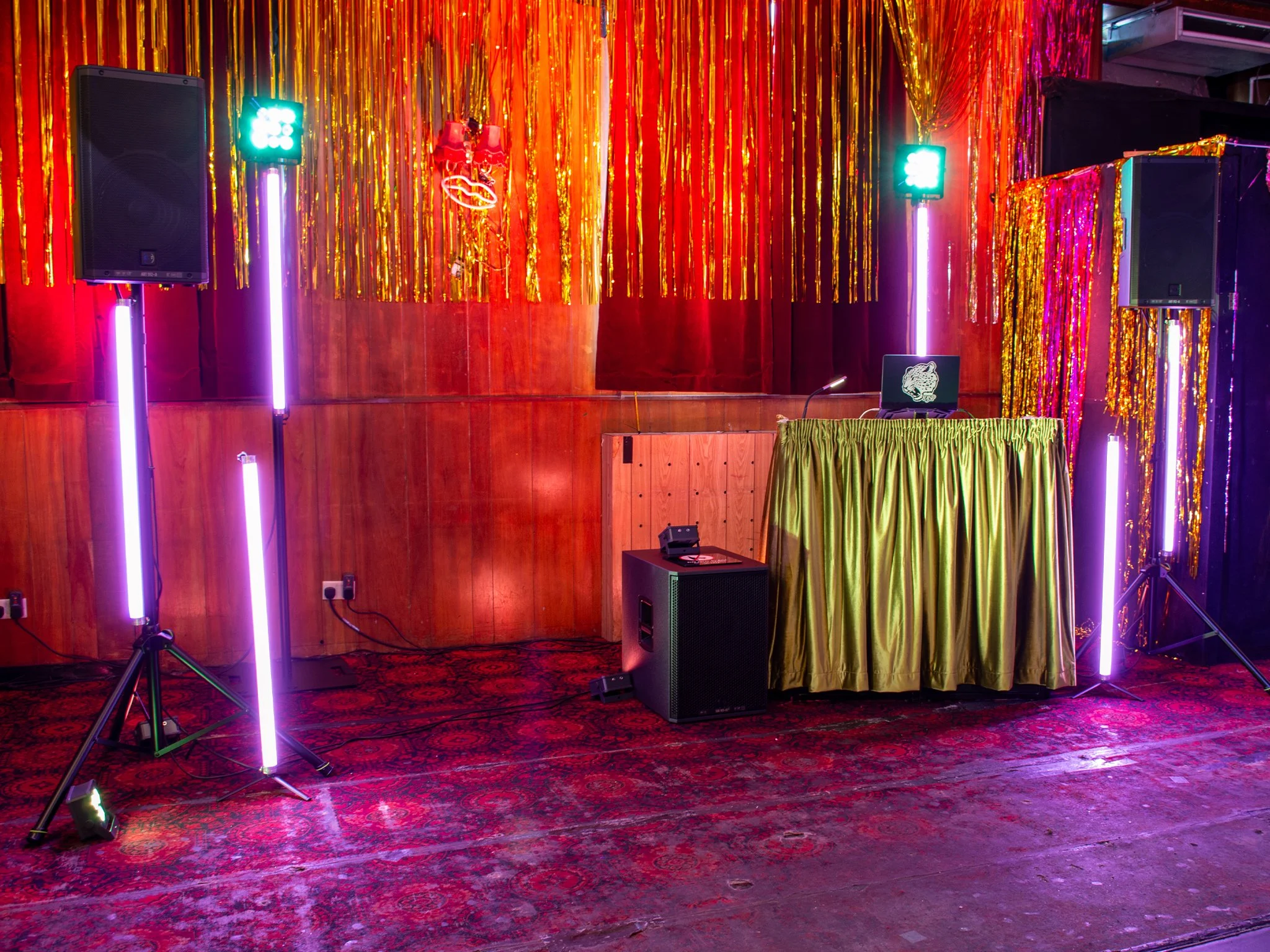 DJ Safari Phil's set up, including speakers, monitors, strip lights and a chartreuse green DJ booth.