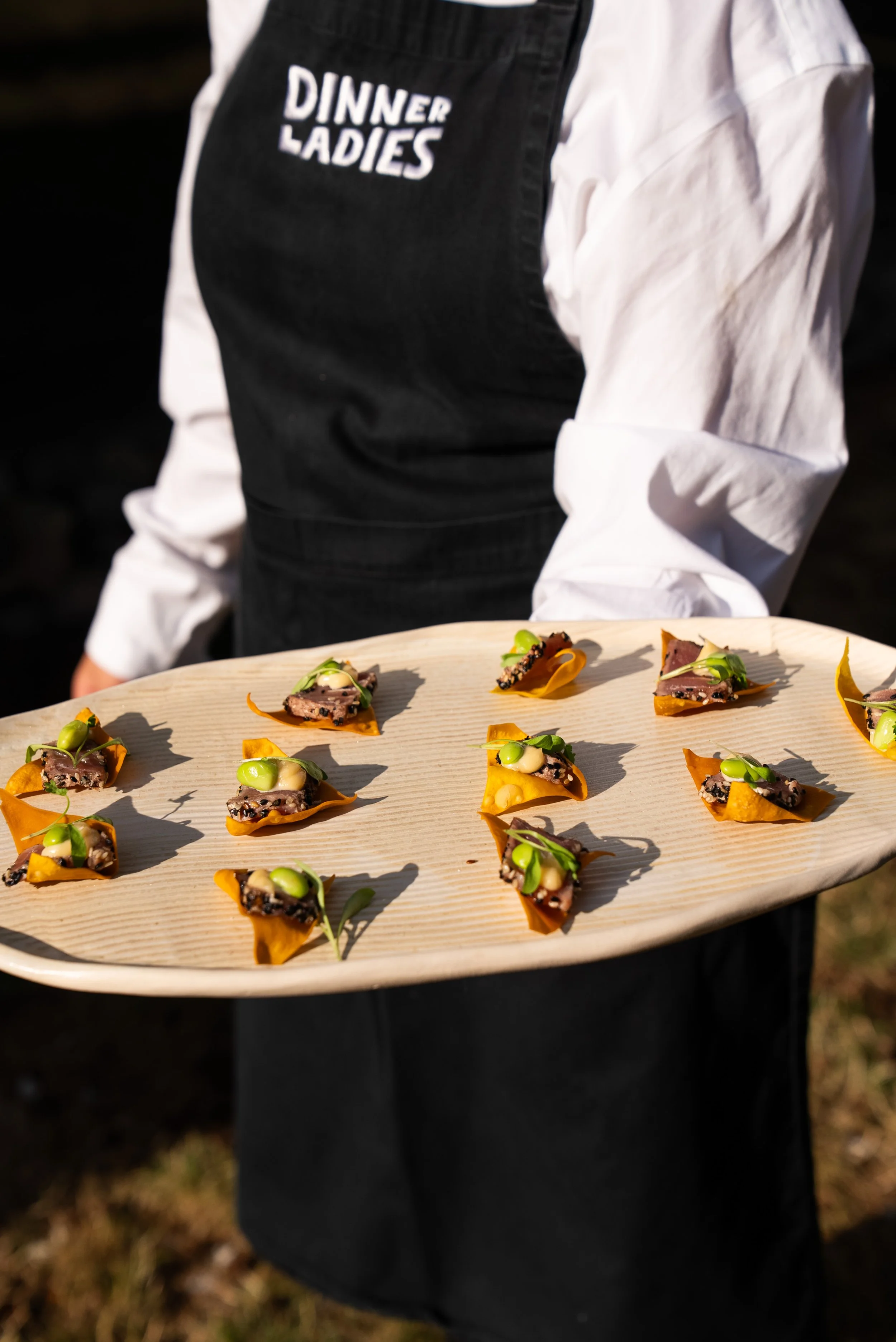 A colouful platter of filo pastry canapes being served at a wedding by someone wearing a Dinner Ladies apron.