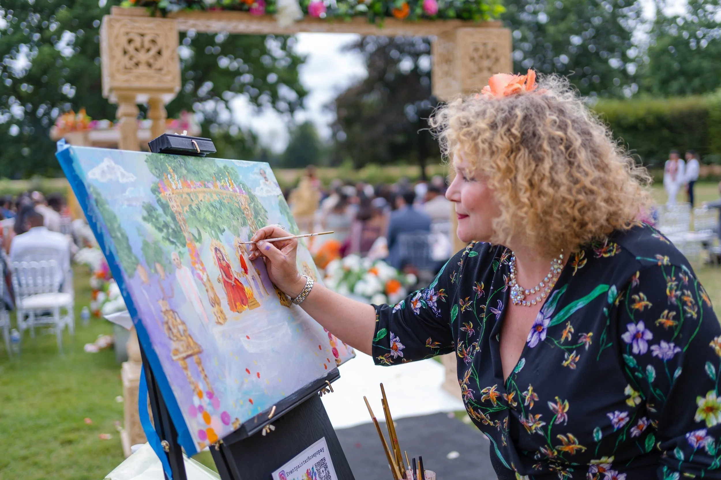 Rose Popay Event Artist painting a live Indian wedding ceremony on canvas, capturing the couple and vibrant details in real time.
