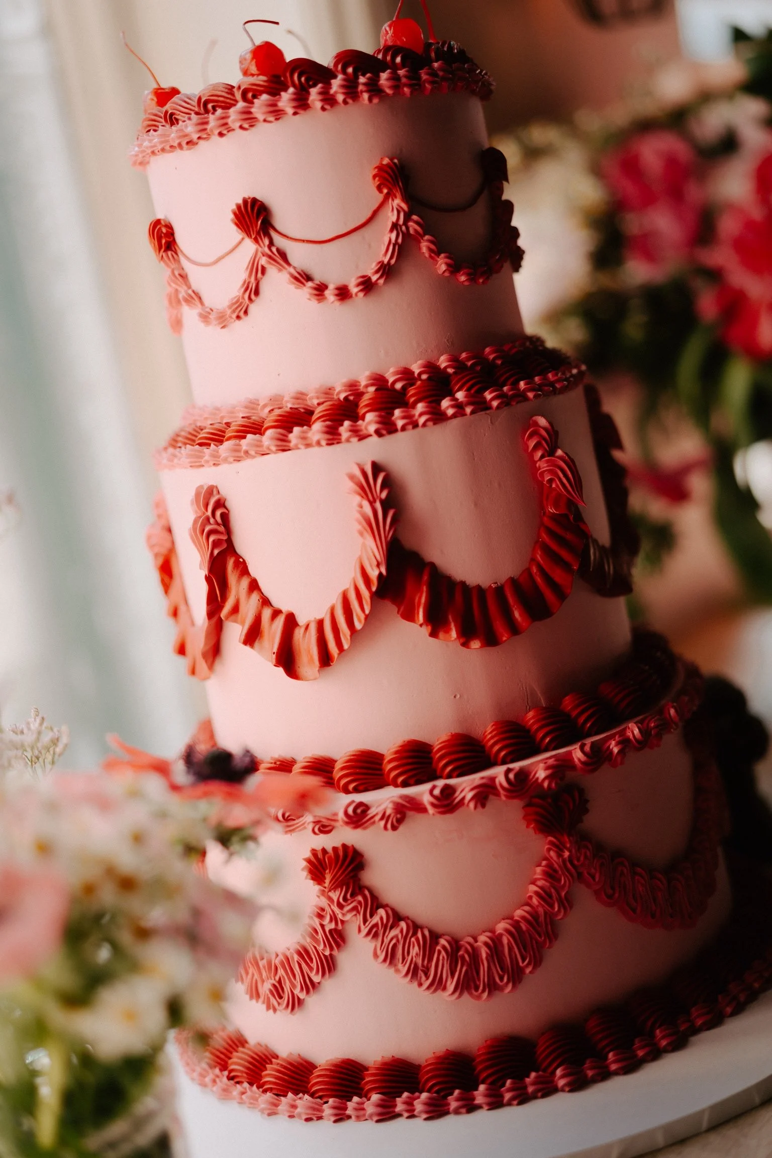 A perfect 3 tier wedding cake with red and pink buttercream icing by Amelia Le Bruin.