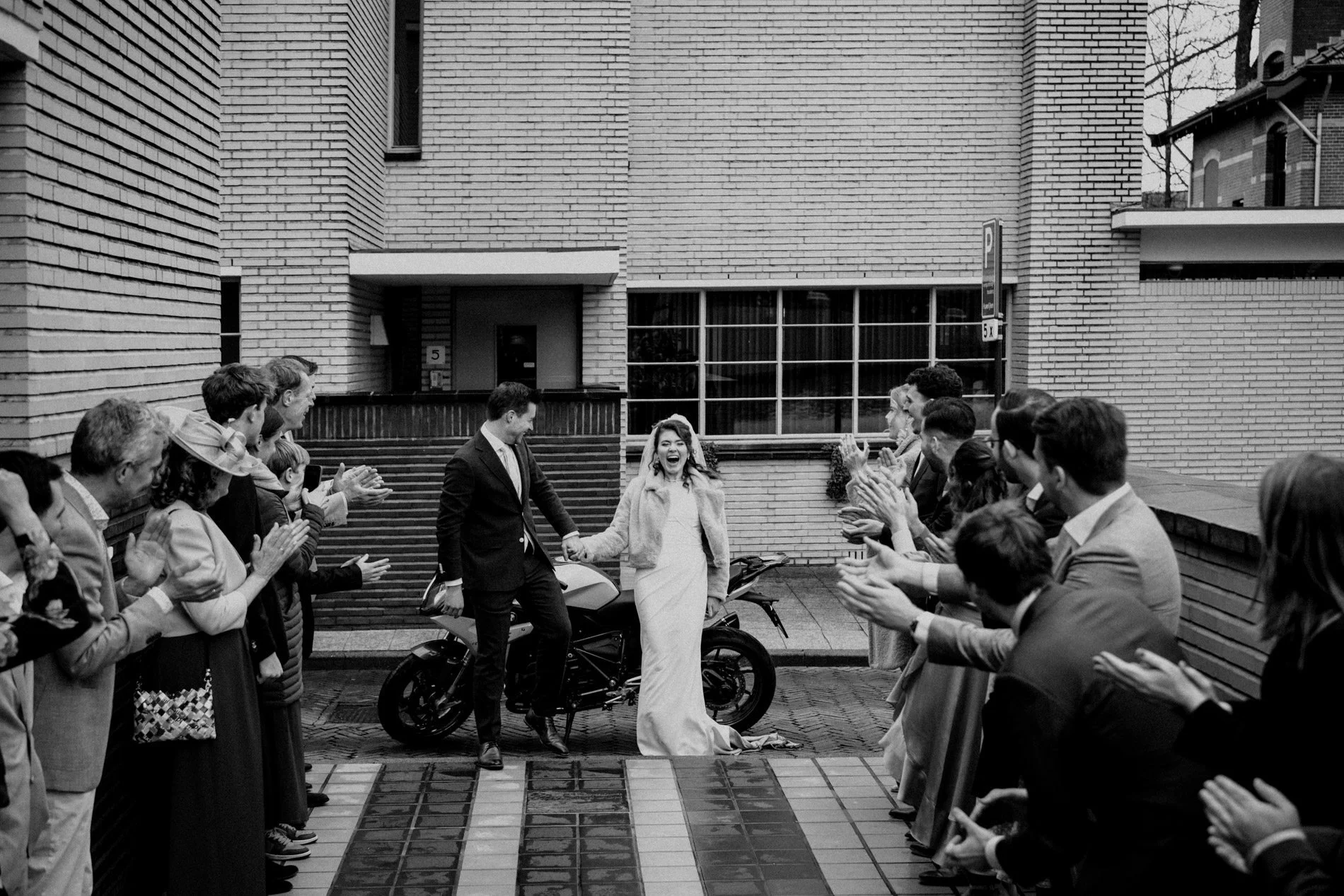 A joyful black and white wedding exit as the couple walk hand in hand through applauding guests, captured in a candid, documentary style by Quiet Mornings Wedding Photography in Scotland.