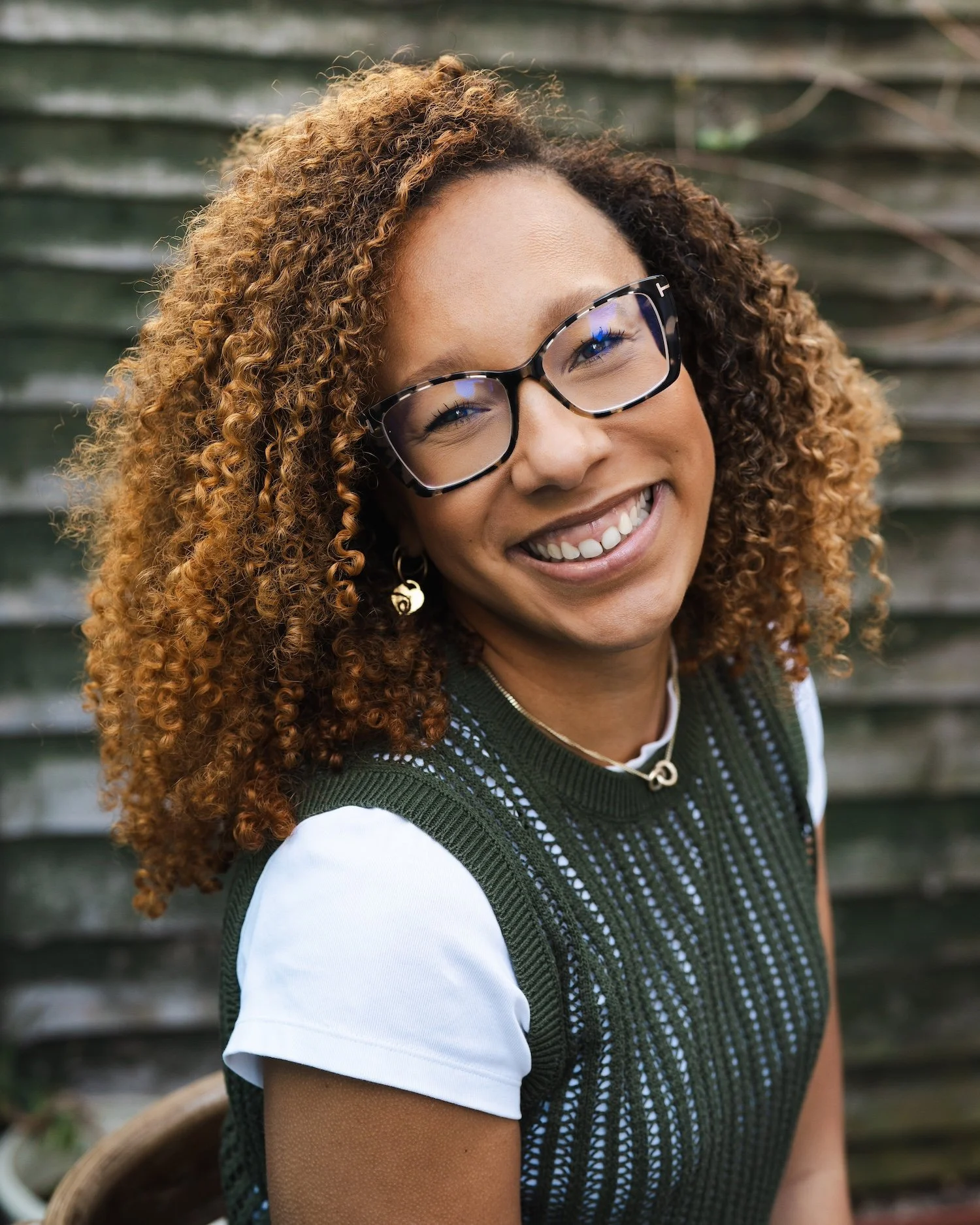Amelia Le Bruin is smiling at the camera. She has curly hair and glasses.