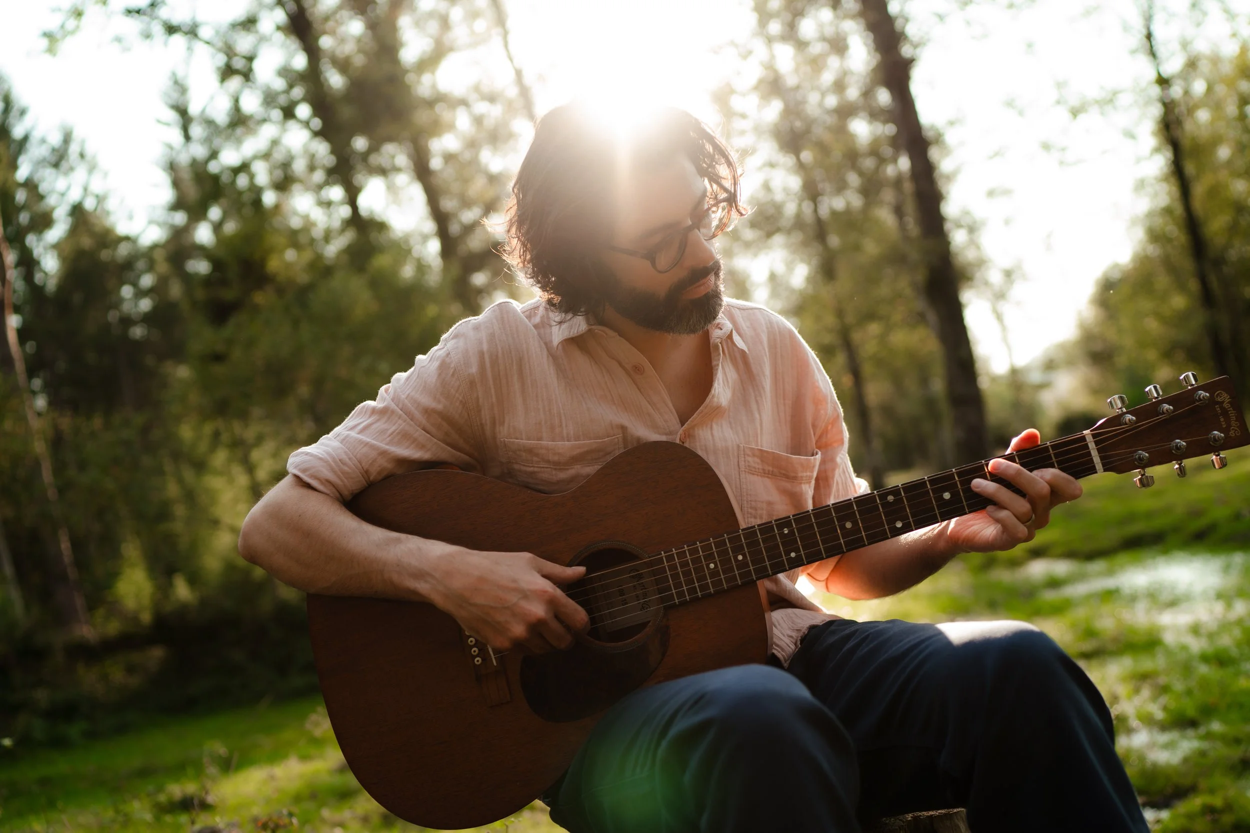 Thomas J Wilman performs an intimate acoustic set outdoors, playing guitar in the soft afternoon sunlight. His warm tone and heartfelt delivery make him a popular choice for relaxed outdoor weddings and acoustic celebrations. Clarkie Photography.