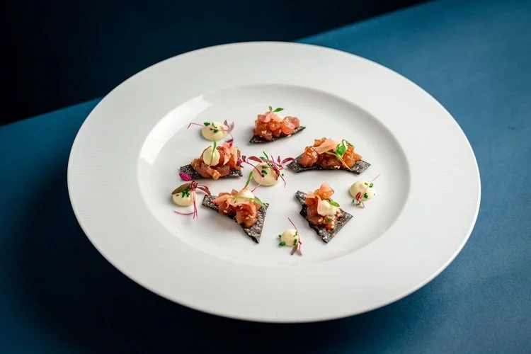An elegant fine dining starter by Hardy’s Catering, featuring delicate salmon tartare served on crisp black sesame crackers with smooth lemon aioli and micro herbs. Beautifully plated on a white dish, this refined canape highlights Hardy’s modern app