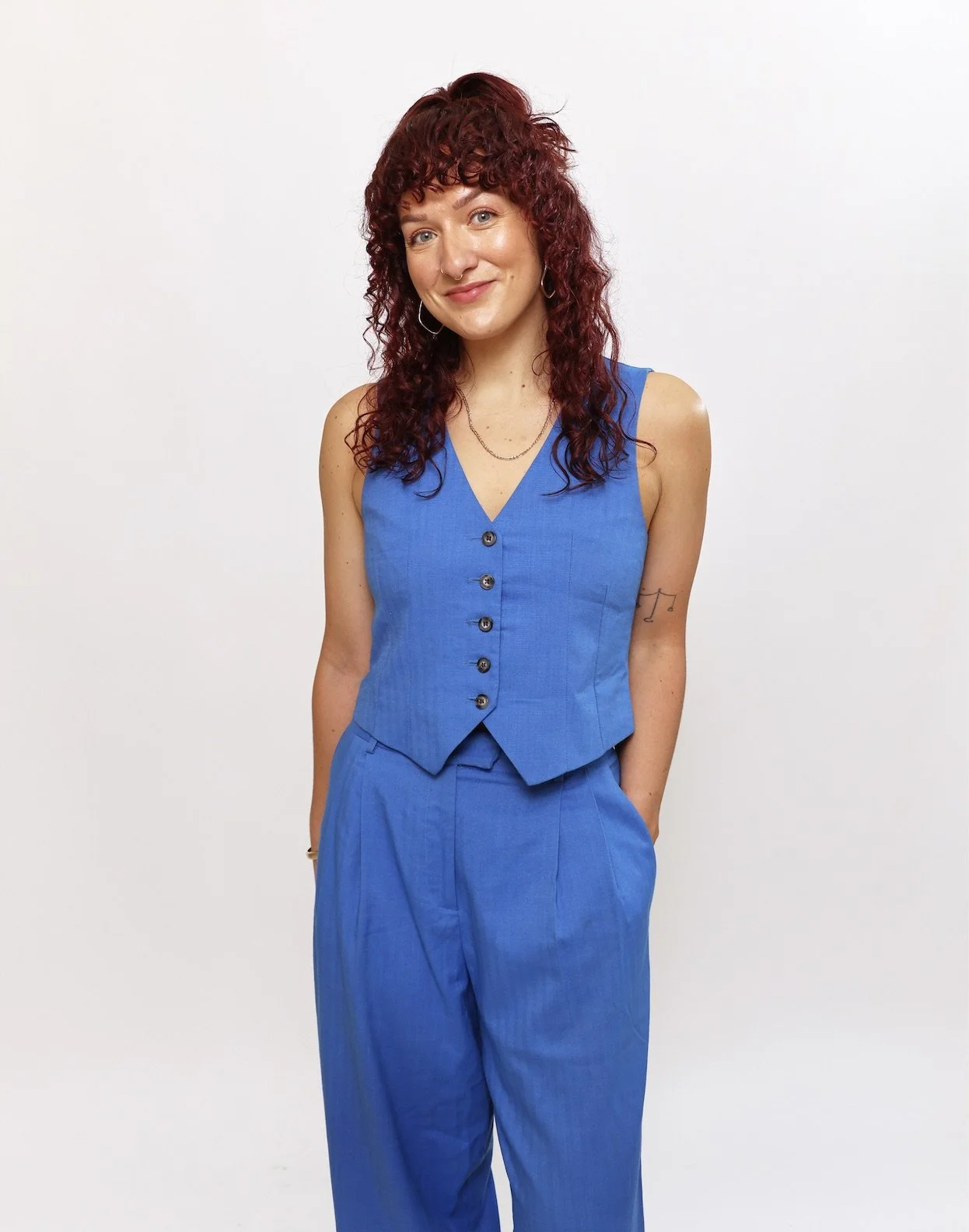 A smiling Robyn Smith Wedding Celebrant stood in front of a white background wearing a blue waistcoat and trousers.