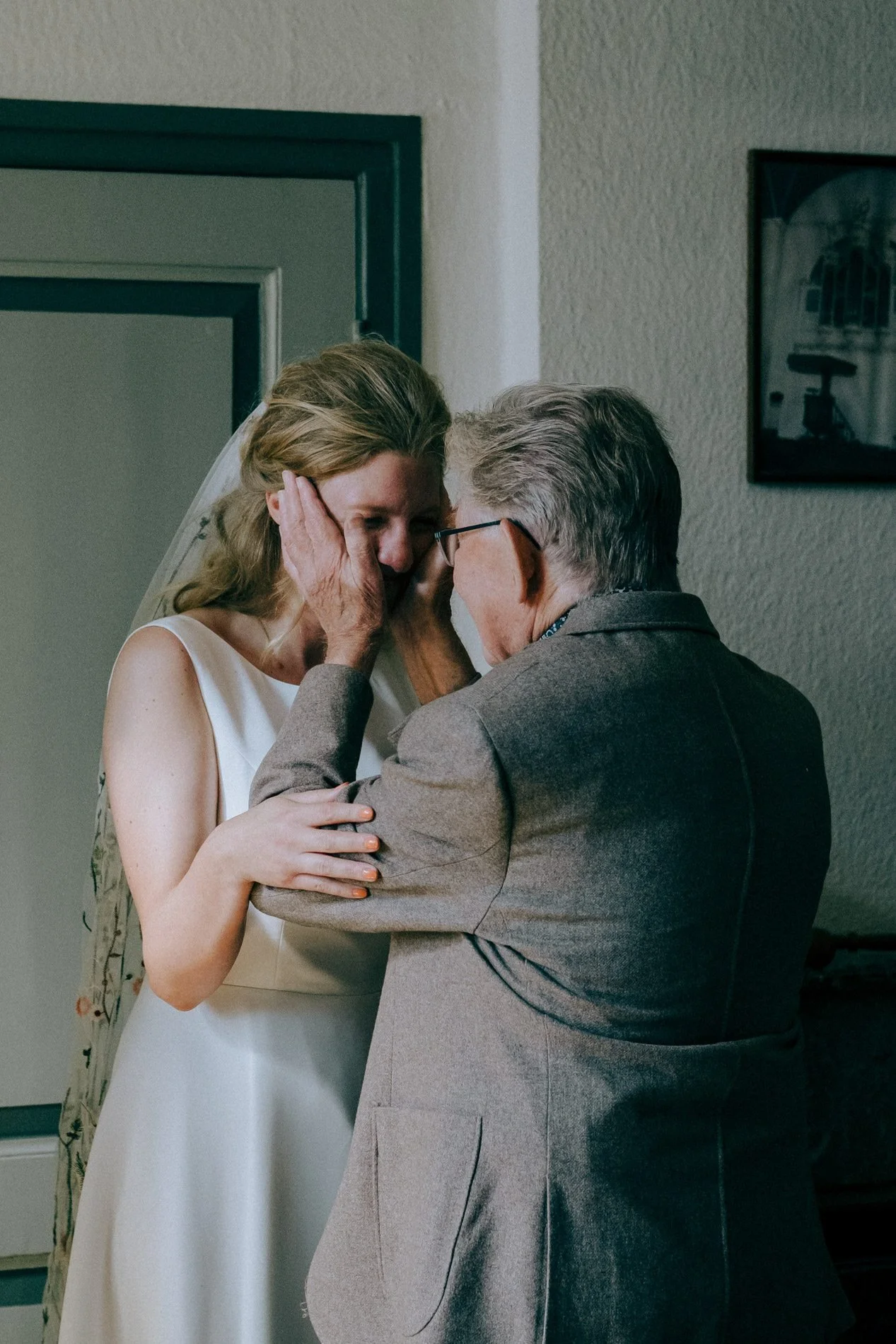 An elegant lace wedding dress hangs on a staircase in soft natural light, capturing calm bridal morning details by Quiet Mornings Wedding Photography in Scotland.