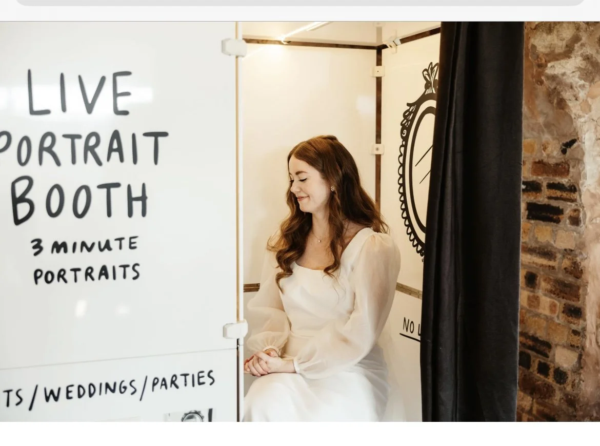 A wedding guest sits gracefully inside the Rubbish Portraits live booth by Lucie Sheridan, waiting for her three-minute hand-painted portrait. The minimal setup and soft lighting make it an elegant and memorable experience that blends art, personalit