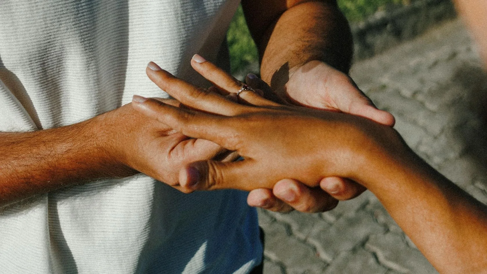 A modern couple getting engaged in London. It's a close up of tanned hands and a unique engagement ring.
