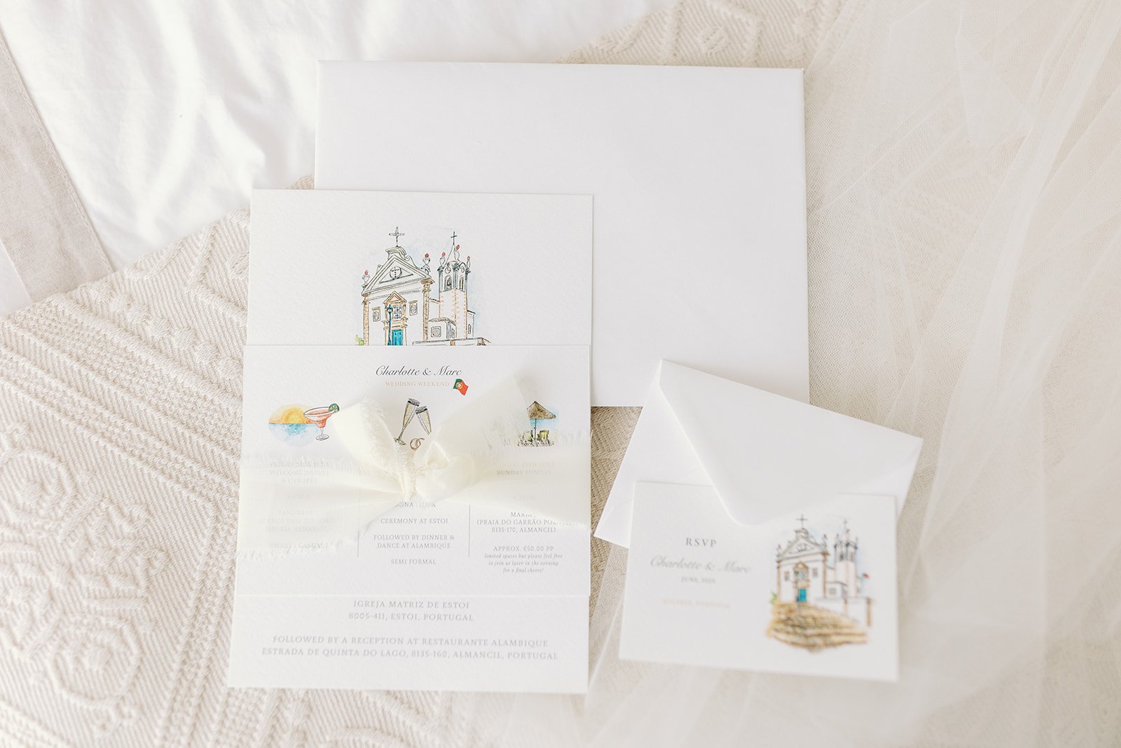 A refined destination wedding invitation suite by Feather & Ink Stationery featuring a delicate watercolour illustration of the couple’s ceremony church in Portugal paired with coordinating RSVP card, itinerary details and soft white envelopes all ti