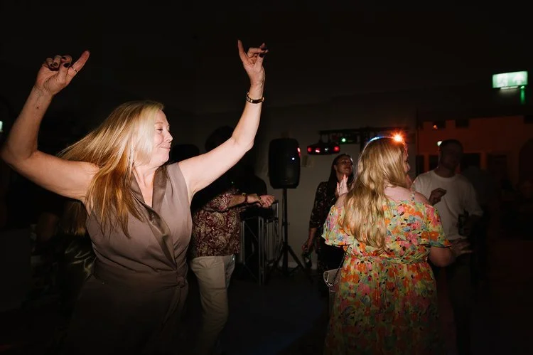 Guests dance joyfully at a wedding reception as The Best Men wedding DJs keep the energy high. The warm lighting and lively atmosphere capture the fun, feel-good vibe of the evening entertainment.