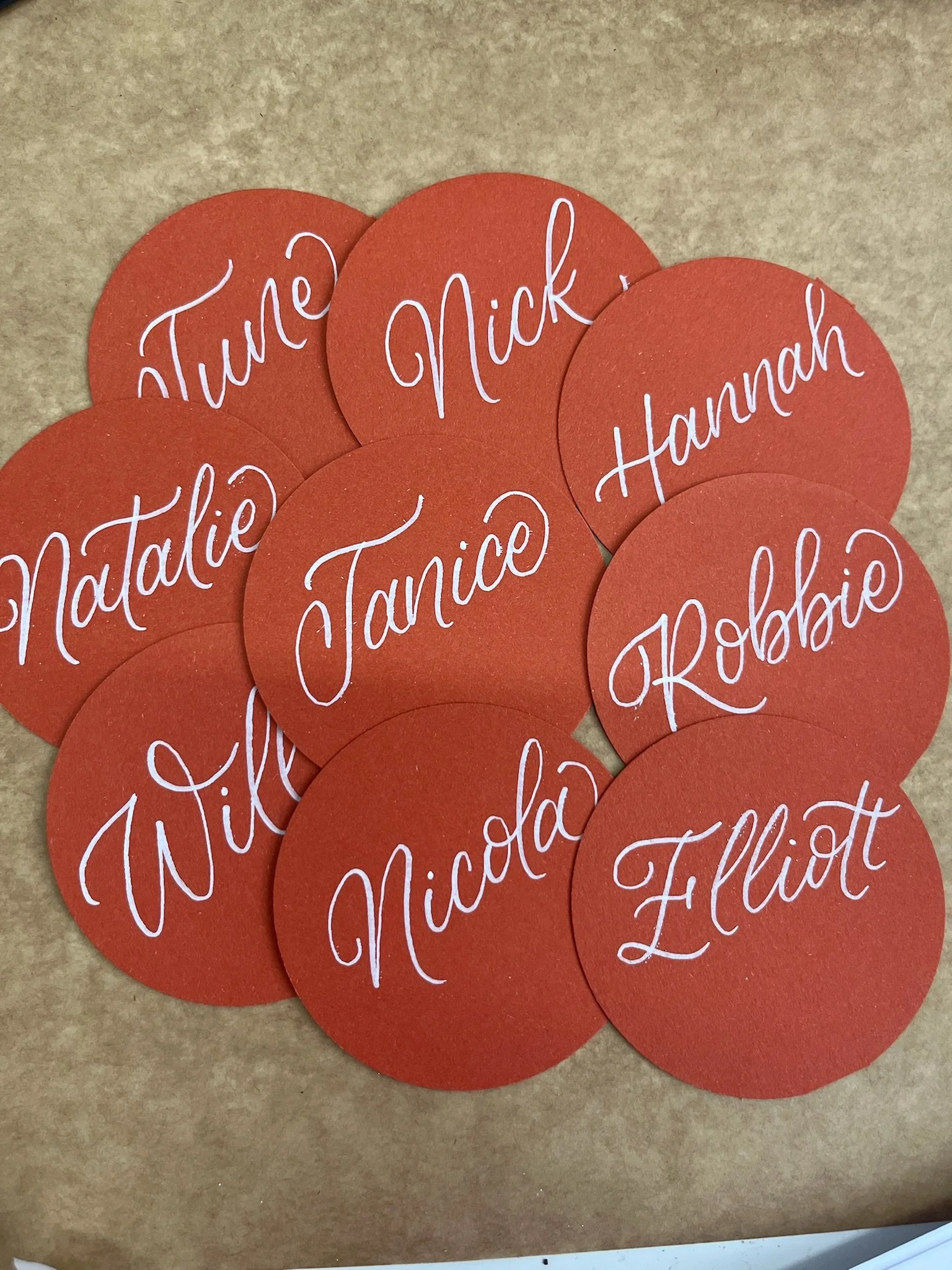 Hand-lettered wedding place cards by Toasty Type, featuring modern calligraphy on circular card stock in a warm, earthy palette. Designed and made in Glasgow, these bespoke wedding stationery details offer a clean, contemporary look while adding a pe