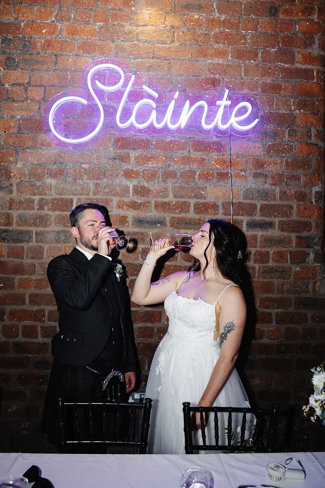 Cheers! Oliver and Marie enjoying a drink beneath a neon sign reading 'Slainte'.