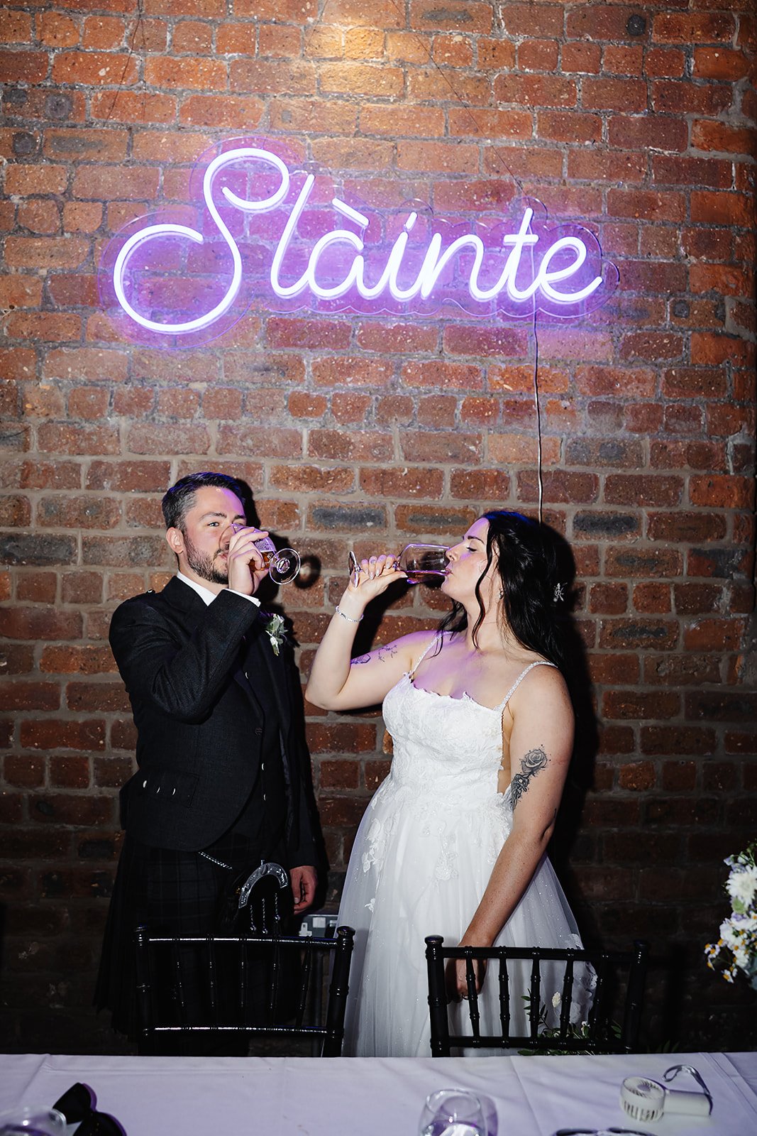 Cheers! Oliver and Marie enjoying a drink beneath a neon sign reading 'Slainte'.