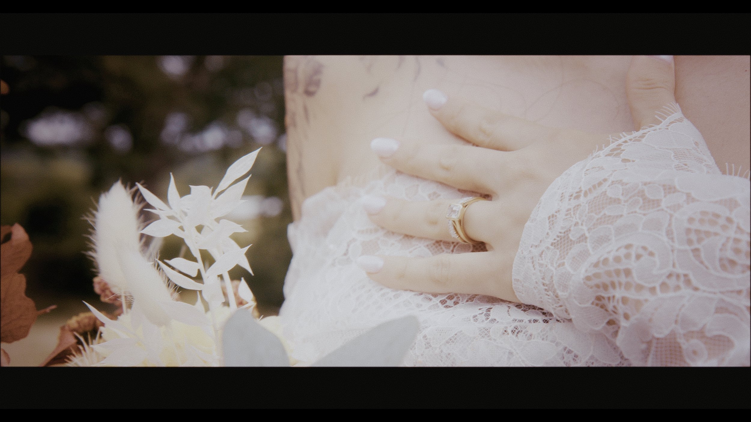 A close-up cinematic shot of a bride’s hand resting gently on her lace wedding gown, showcasing her elegant engagement ring and delicate white manicure. Captured by Heart Shaped Video, this intimate moment highlights their signature romantic and time