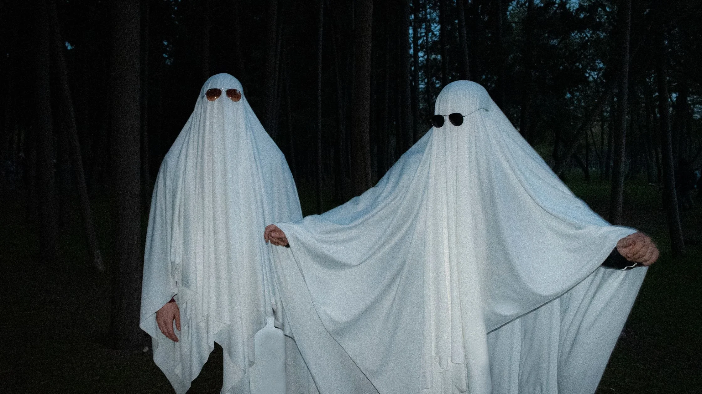 2 people dressed as ghosts wearing sheets and sunglasses. They are pretending to ghost their wedding suppliers.