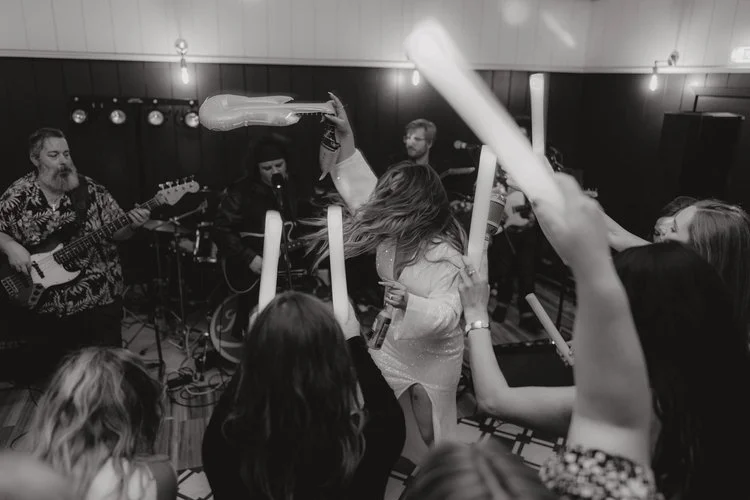 A bride dances at the centre of a packed wedding dancefloor as the live band plays behind her, captured with powerful energy and atmosphere by F.D Young Photography. Guests raise glow sticks in celebration while the bride’s hair moves with the music,