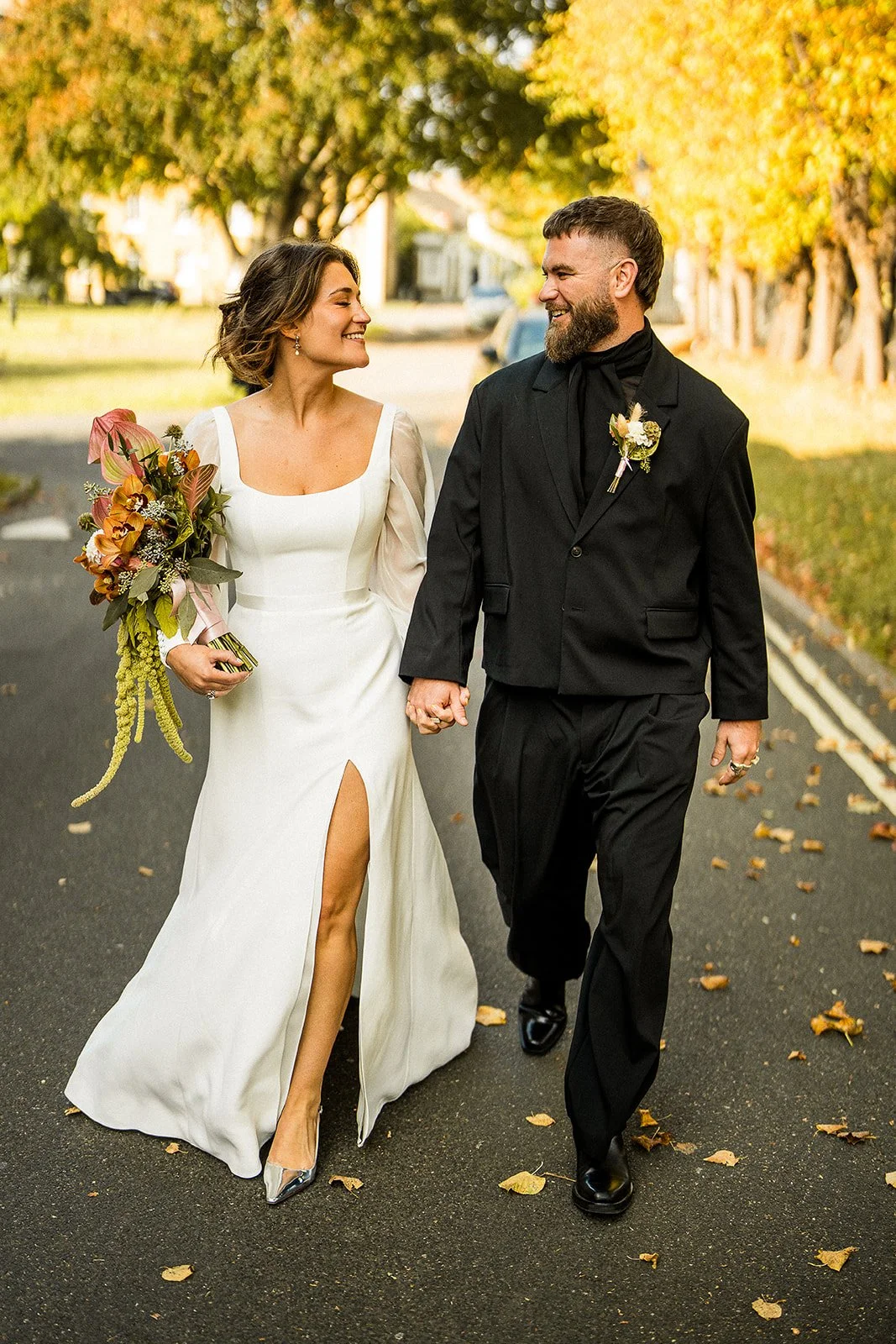 A bride and groom walking down the street on their wedding day.
