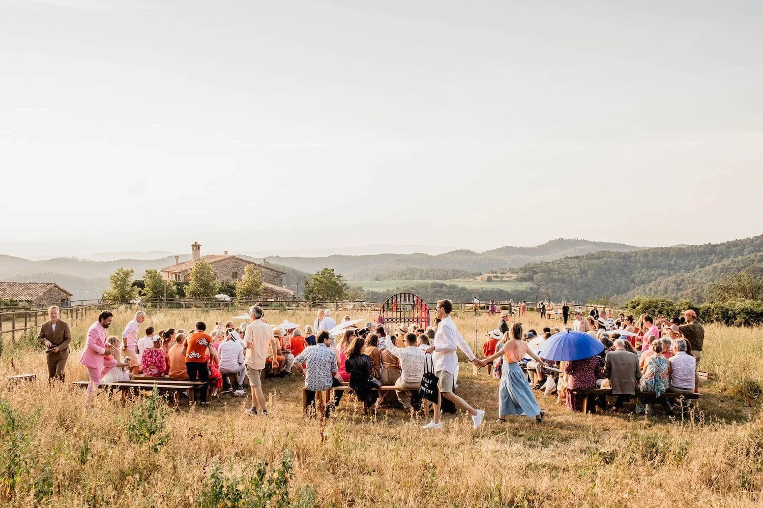Wedding guests enjoying a colourful, outdoor wedding ceremony at 'This Must Be The Place, located in the Spanish Hills of Barcelona.