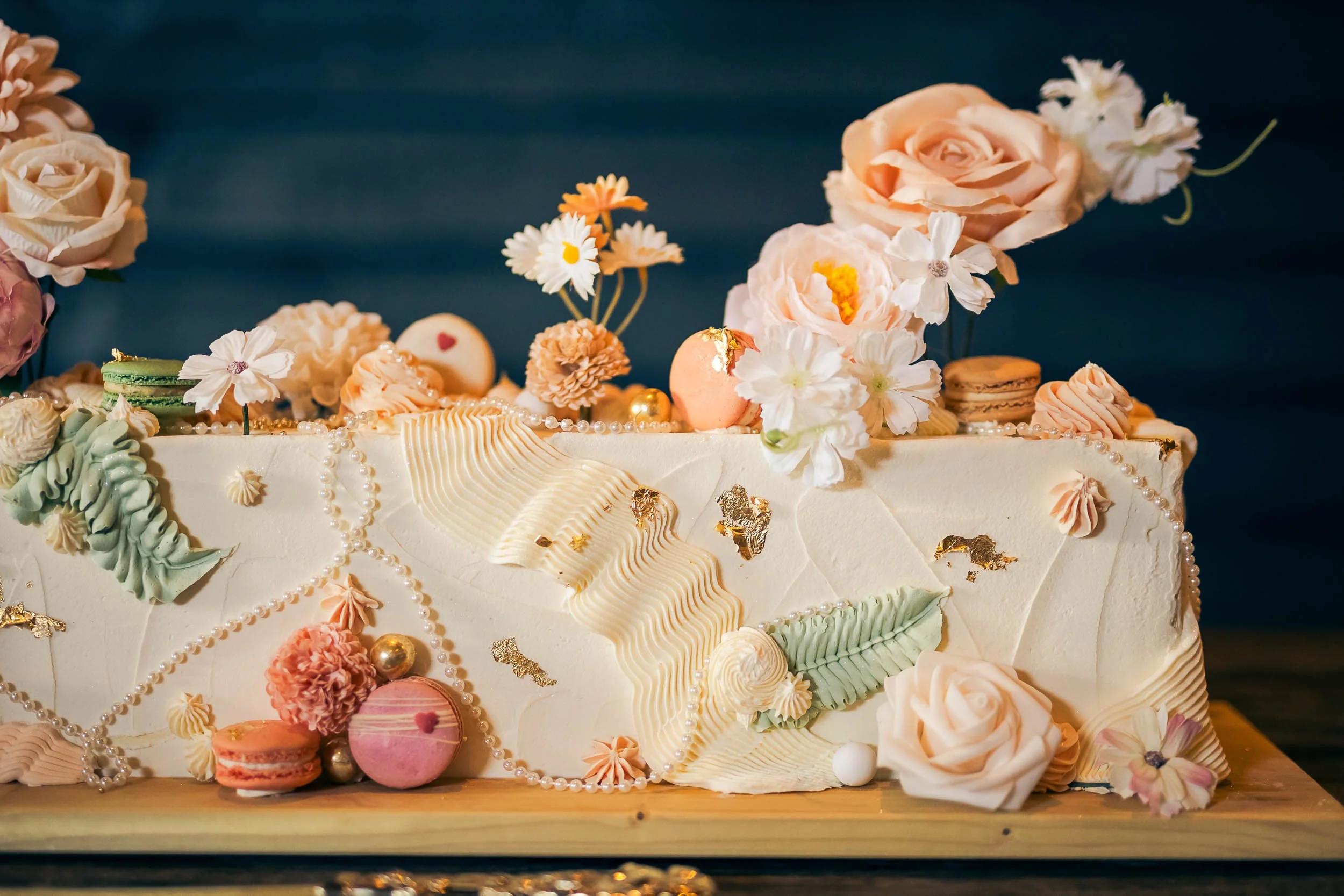 A close up of a summery wedding cake with fresh flowers.