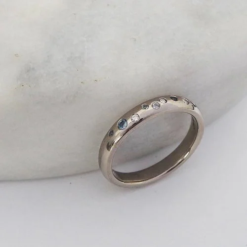 Handcrafted silver wedding ring with scattered diamonds and sapphires by Daniel Darby Jewellery Designer. Made in the UK, this bespoke band combines subtle sparkle and timeless elegance for modern brides and grooms.