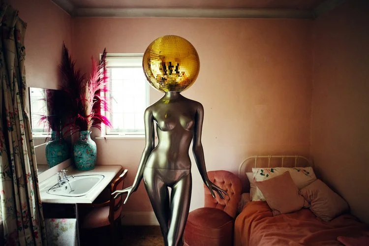 My Colour is Gold silver mannequin with a golden disco ball head, styled in a retro-inspired pink room for a unique and playful event feature.