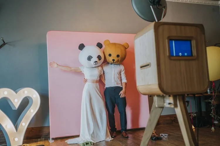 A couple shares a playful photo booth moment wearing oversized panda and bear heads against a pink backdrop, captured by Viva La Booth’s signature wooden setup. This shot perfectly reflects the brand’s mix of charm, style, and humor, creating joyful 