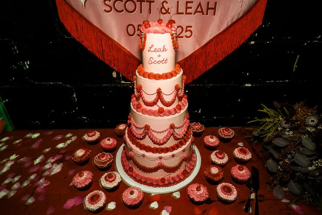 Retro-inspired tiered wedding cake by The Cake Hun featuring vintage piping, soft pink buttercream and bold red detailing, styled with matching cupcakes. A modern, design-led wedding cake for creative, contemporary weddings, blending nostalgic aesthe