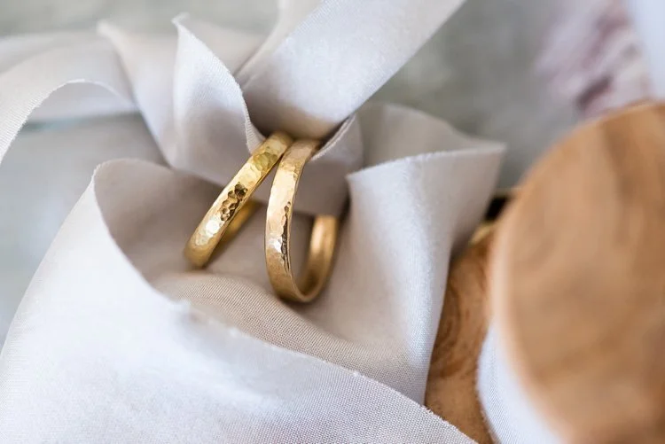 Handcrafted hammered gold wedding rings by Nikki Stark Jewellery, elegantly wrapped in soft fabric. Ethically made in the UK, these timeless bands are perfect for couples seeking bespoke, artisanal wedding jewellery.