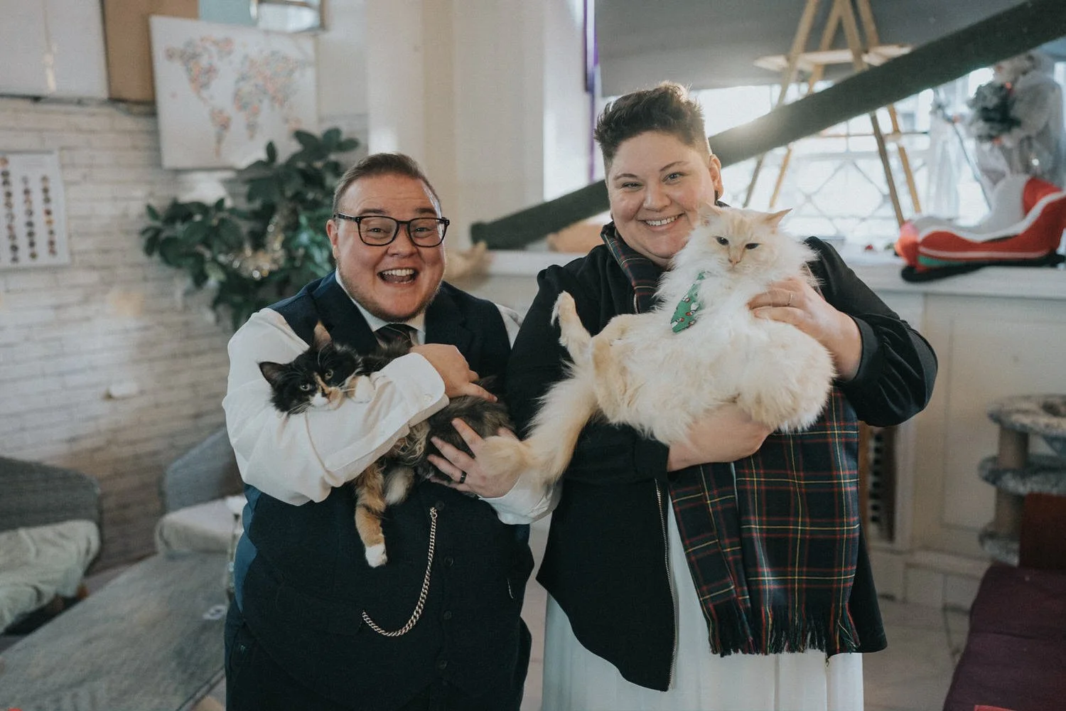 A candid wedding portrait of a smiling couple holding their cats at home, captured by Good Luck Wolf Photography in Glasgow, celebrating a relaxed, personality-filled wedding day with pets, laughter and authentic connection.
