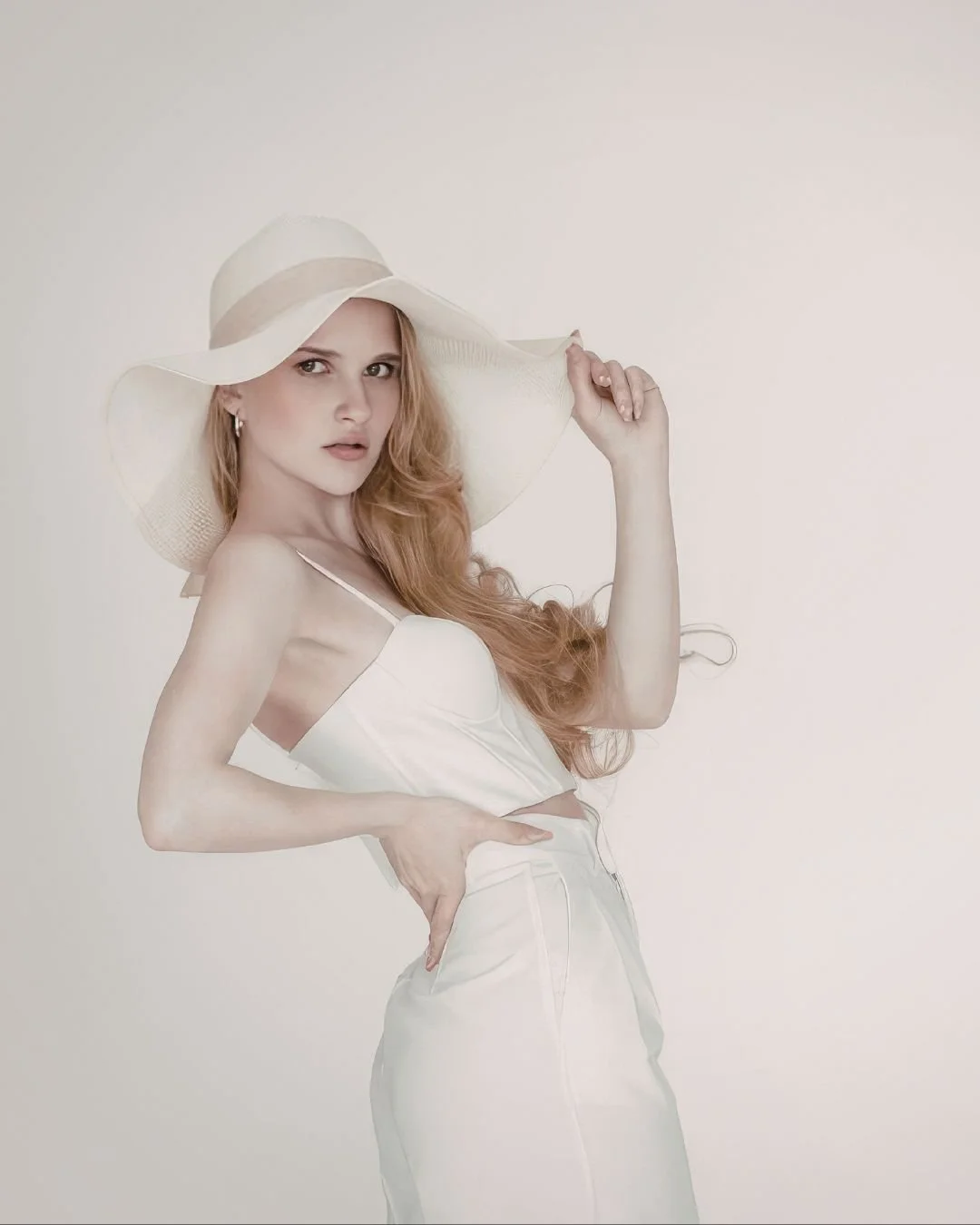 A blonde bride is wearing a white bridal hat inspired by Dua Lipa at her wedding.
