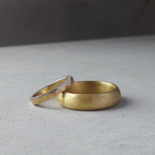 Minimalist gold and silver wedding bands by Daniel Darby Jewellery Designer. Handcrafted in the UK, these contemporary matte-finish rings are perfect for couples seeking simple, elegant, and timeless wedding jewellery.