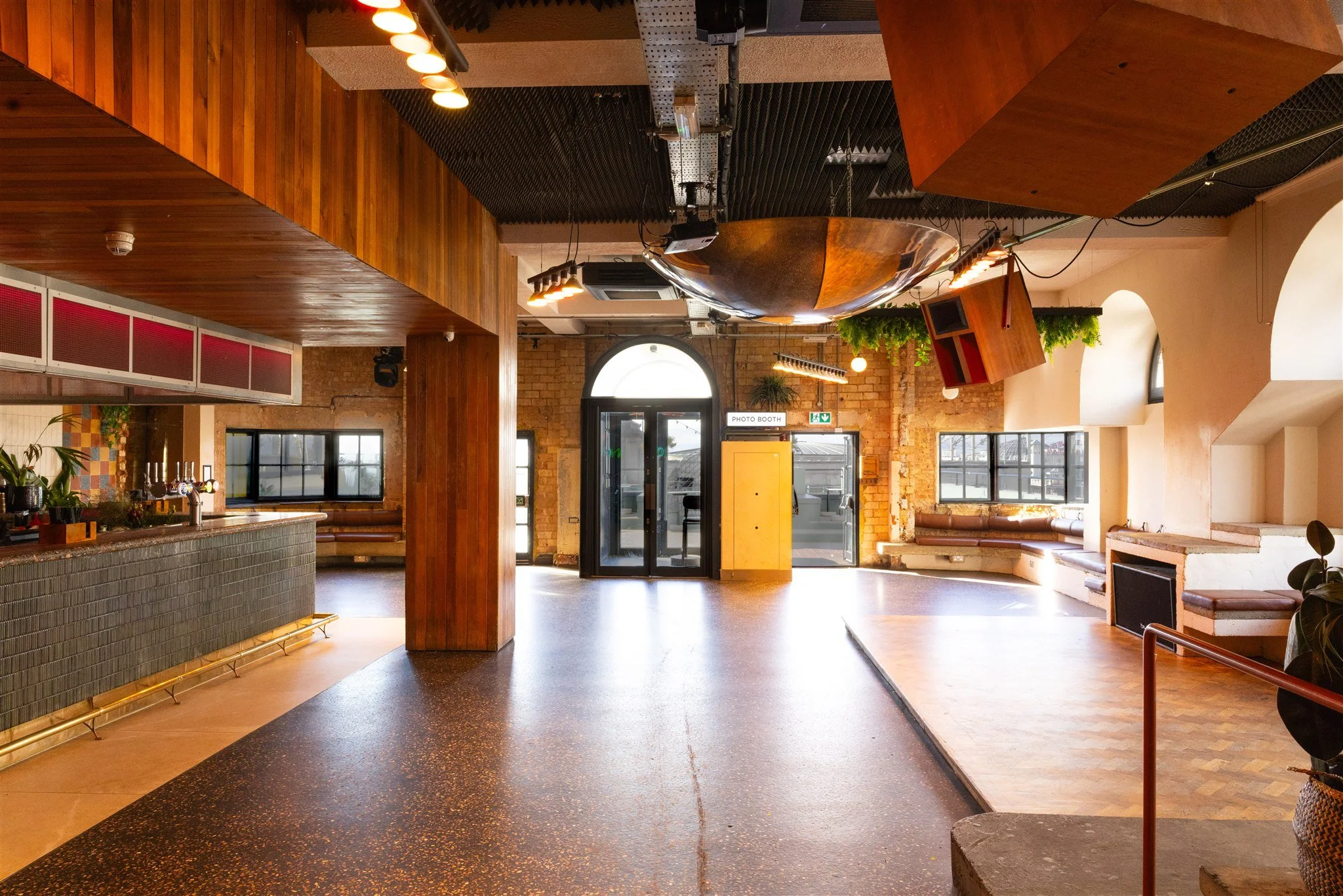 A chic and versatile event space inside Pier Court Brighton, showing the textured granite bar, feature lighting, arched windows, and built-in seating—perfect for relaxed, modern weddings with personality.