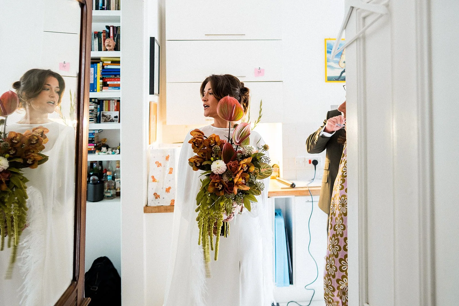 A bride is holding an impressive bouquet and looking in the mirror on the morning of her wedding.