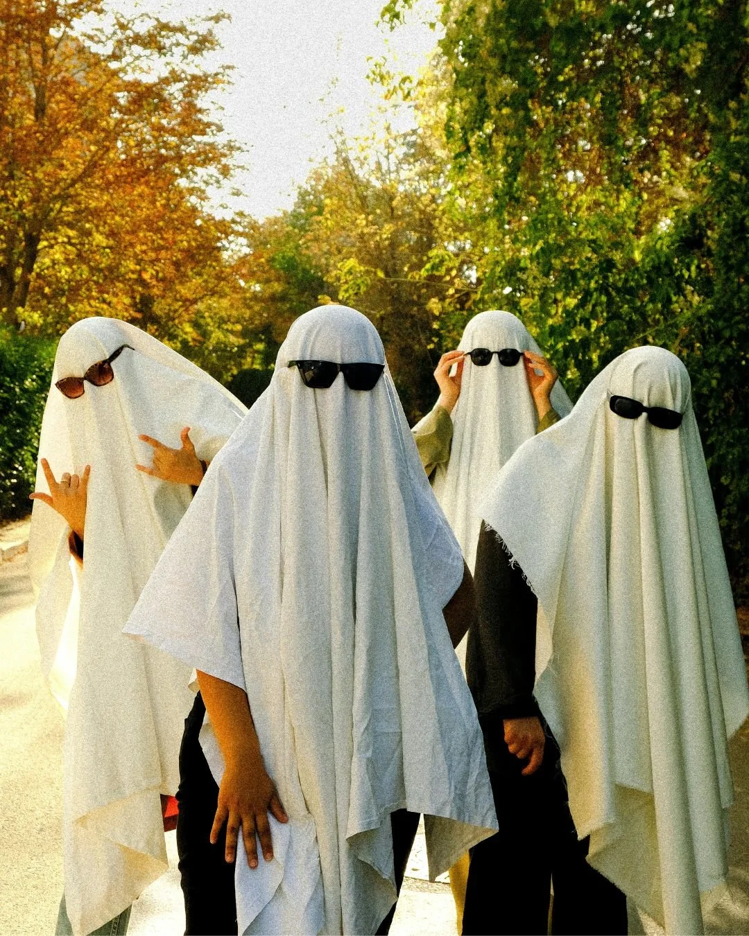 4 people dressed as ghosts wearing shades and sheets.