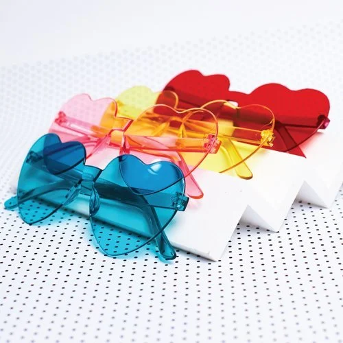 Set of vibrant heart-shaped sunglasses in blue, pink, yellow, and red, styled by Melon Teaspoon as playful accessories for parties and celebrations.