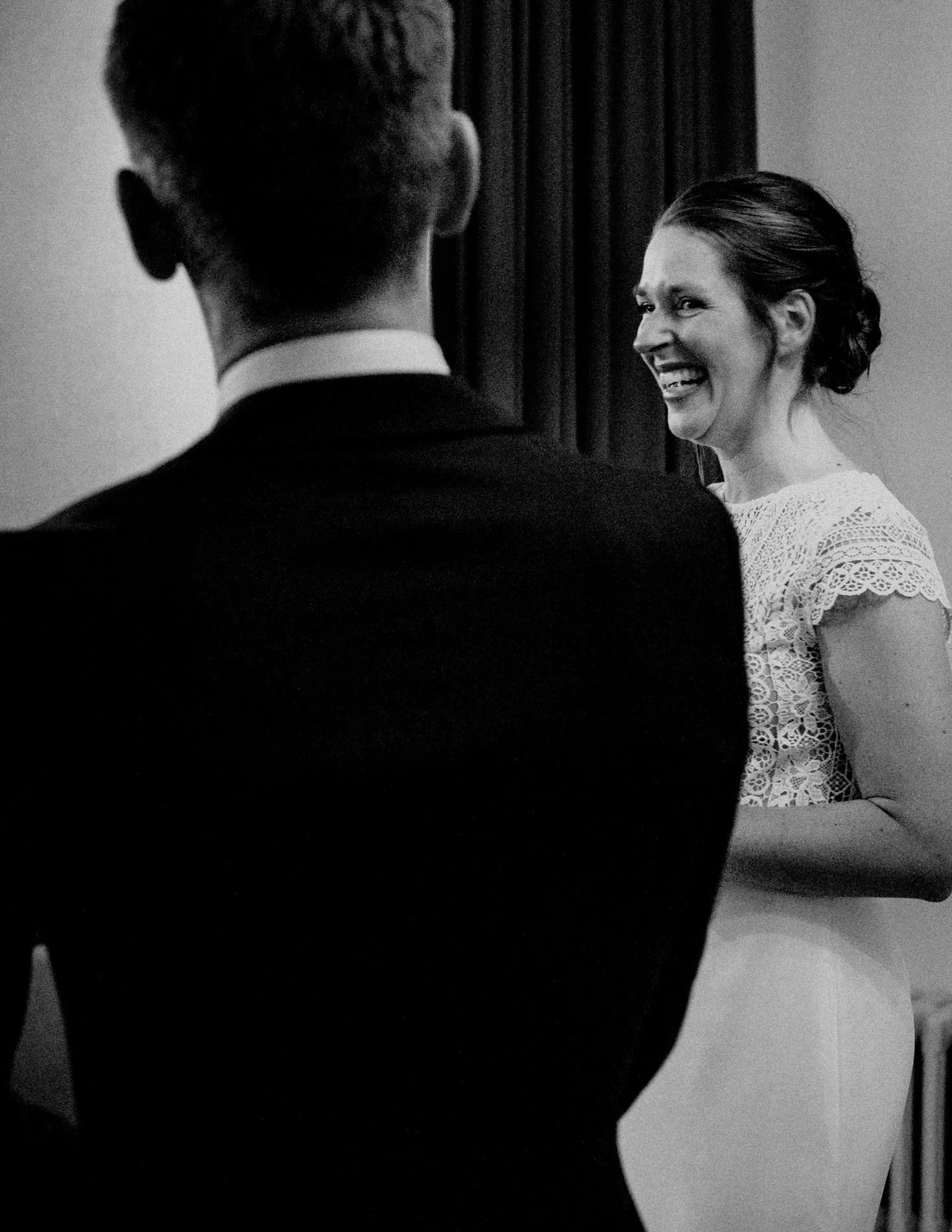 A candid black and white moment of the bride smiling during the ceremony, capturing genuine emotion and connection by Quiet Mornings Wedding Photography in Scotland.