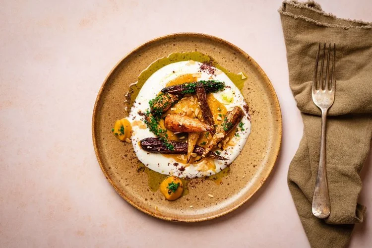 A gourmet roasted root vegetable dish by Hardy’s Catering, featuring caramelised carrots and parsnips served on a bed of creamy purée with herb oil, crushed nuts, and microgreens. This beautifully styled plate highlights Hardy’s focus on flavour, art