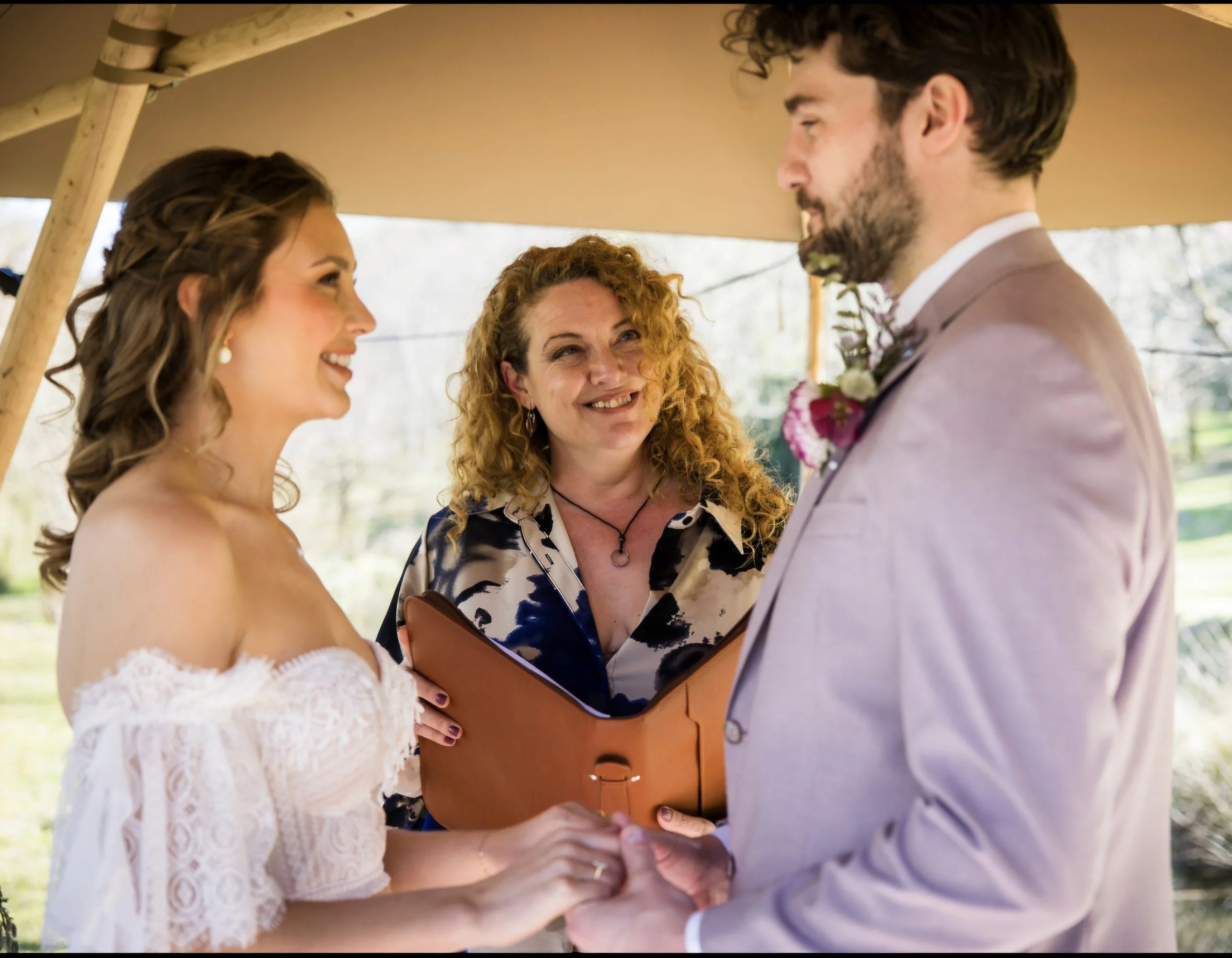 Melly The Celebrant conducting a ceremony with a bride and groom. The bride is in white and the groom is wearing lilac.