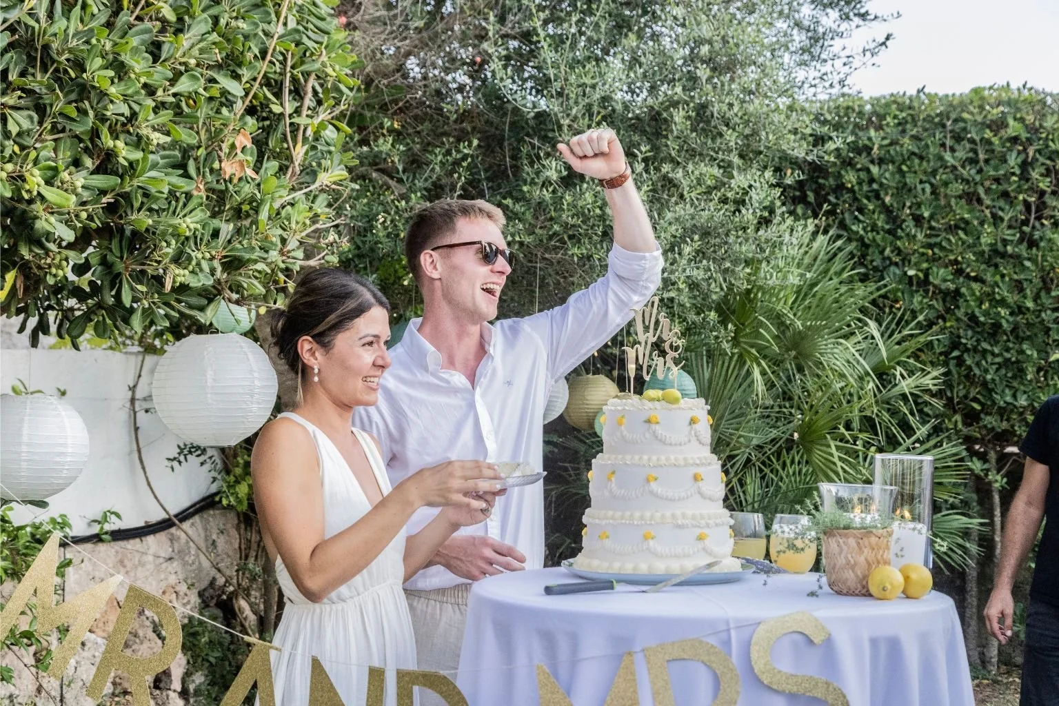 A bride and groom looking really happy with their summery wedding cake by The Cake Hun.