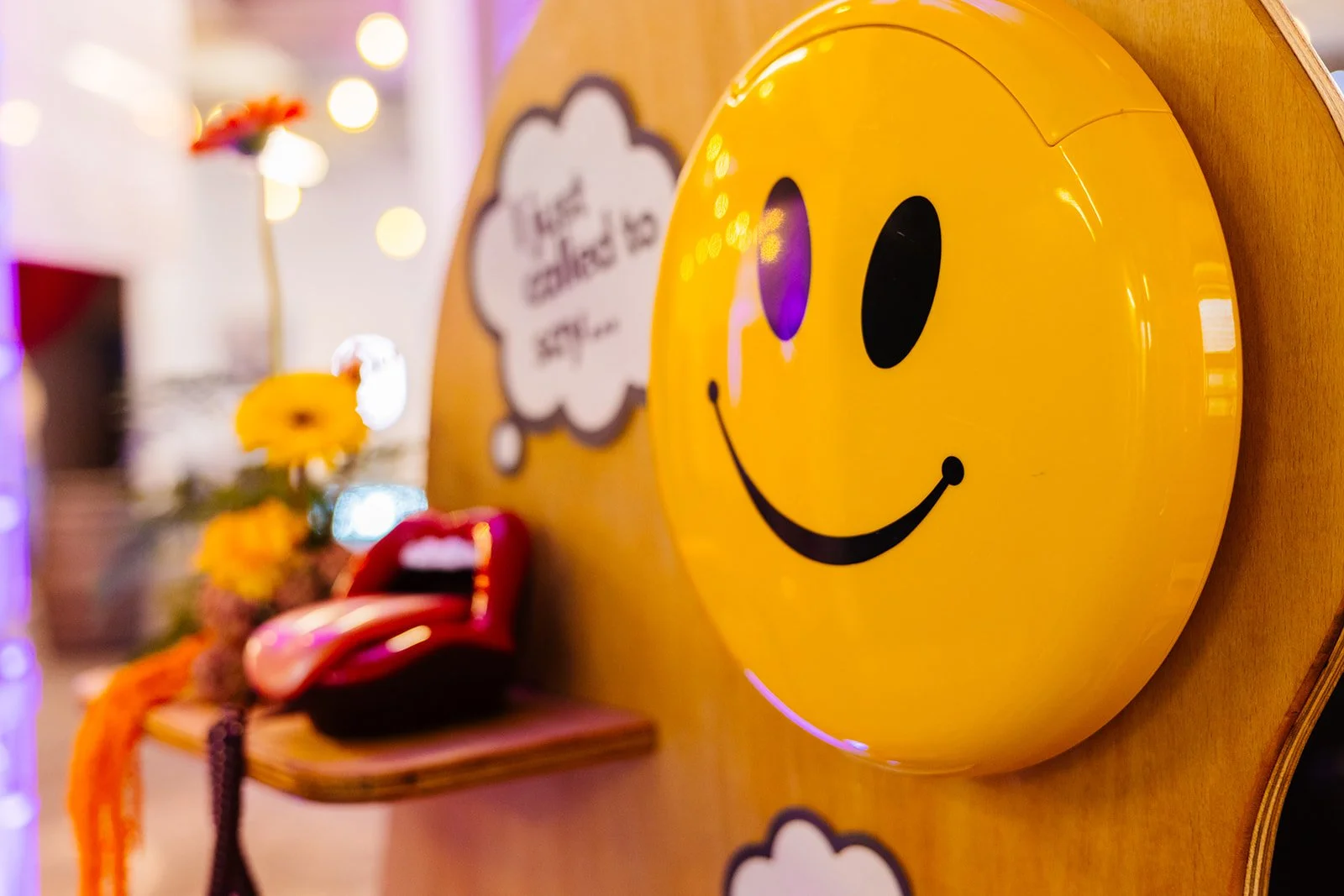 A smiley face audio guest book display at The Un-Wedding Show. There is a red lip shaped phone in the background.