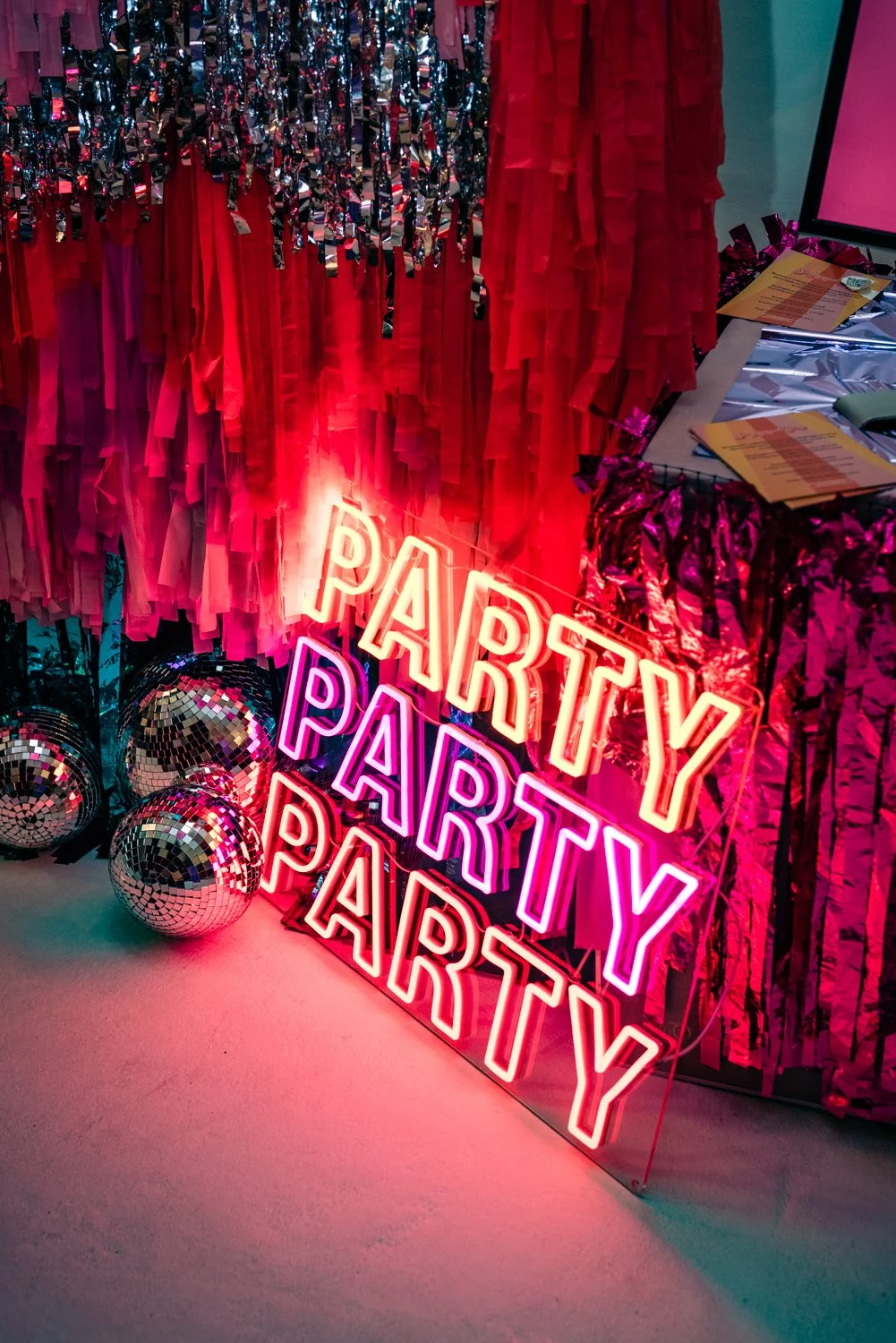 A streamer backdrop by Streamadelica including a neon PARTY sign and some disco balls.
